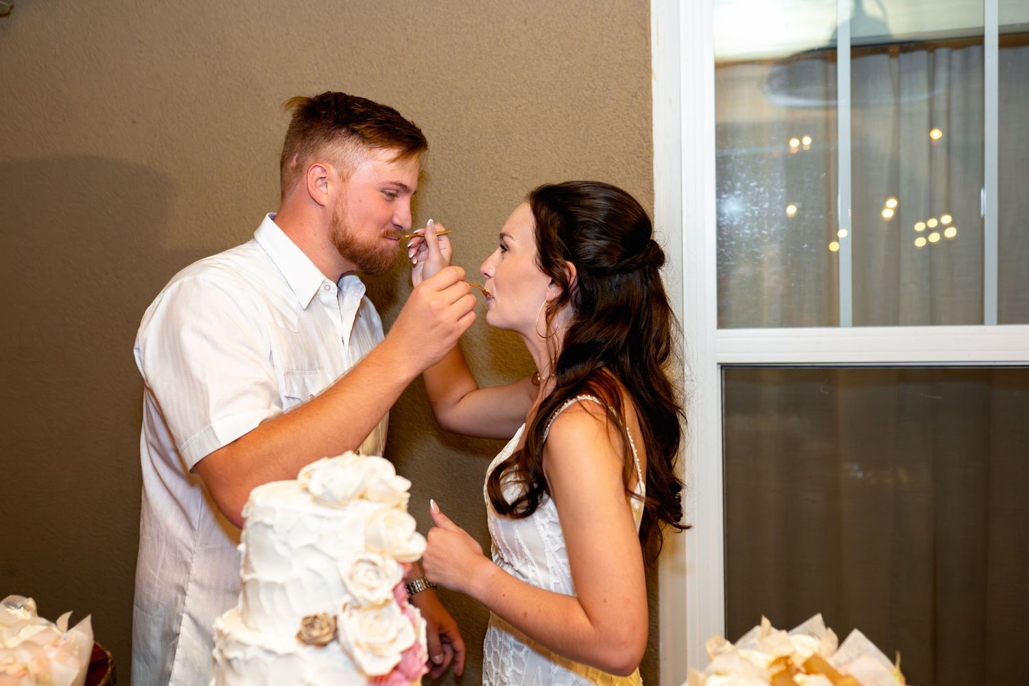 Newlyweds share wedding cake during traditional cake cutting moment at reception.