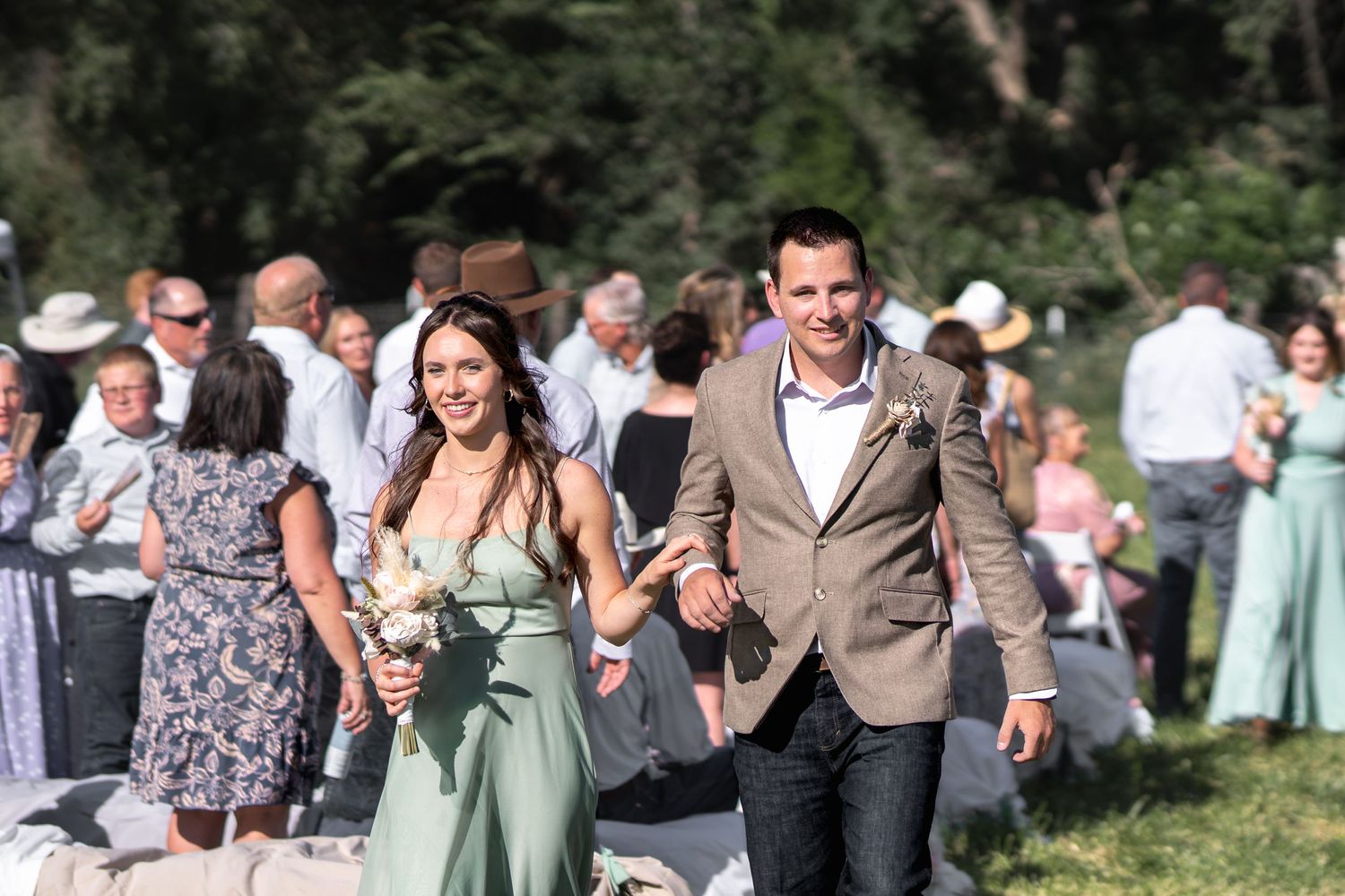 Wedding guests look on as a couple exits their outdoor ceremony with excitement.