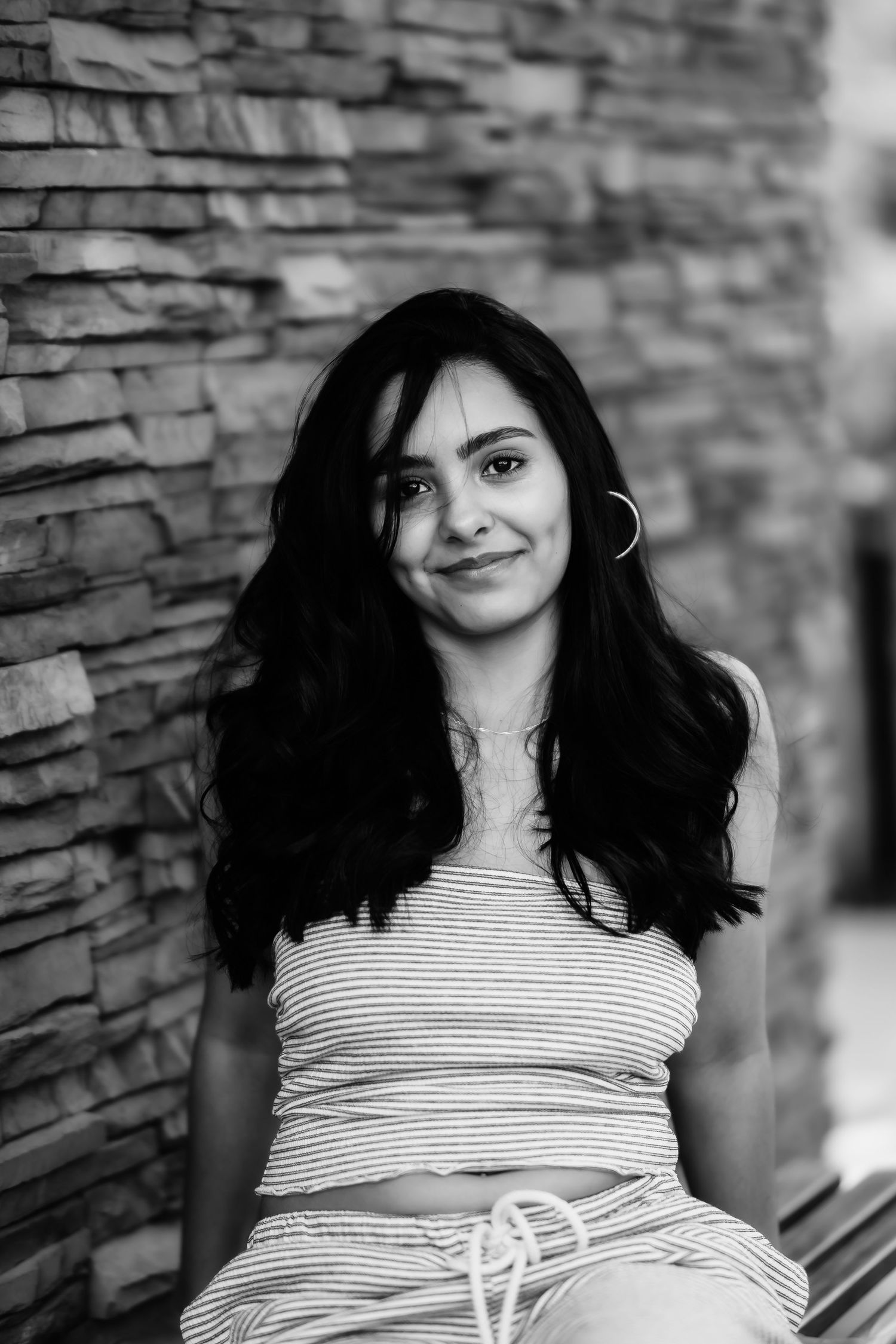 Black and white portrait of woman in striped top against stone wall.
