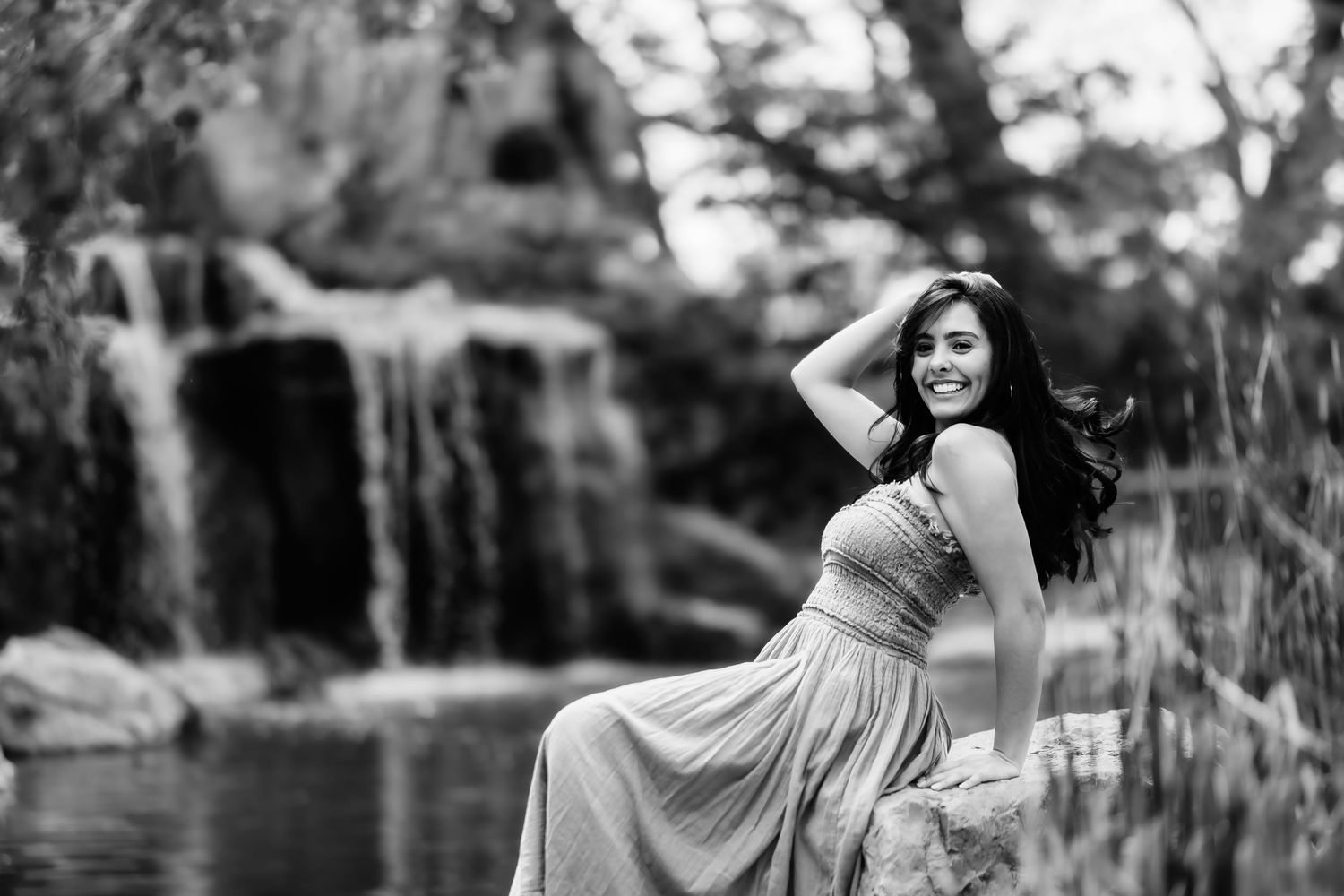 Elegant pose in a maxi dress with cascading waterfall backdrop in monochrome.