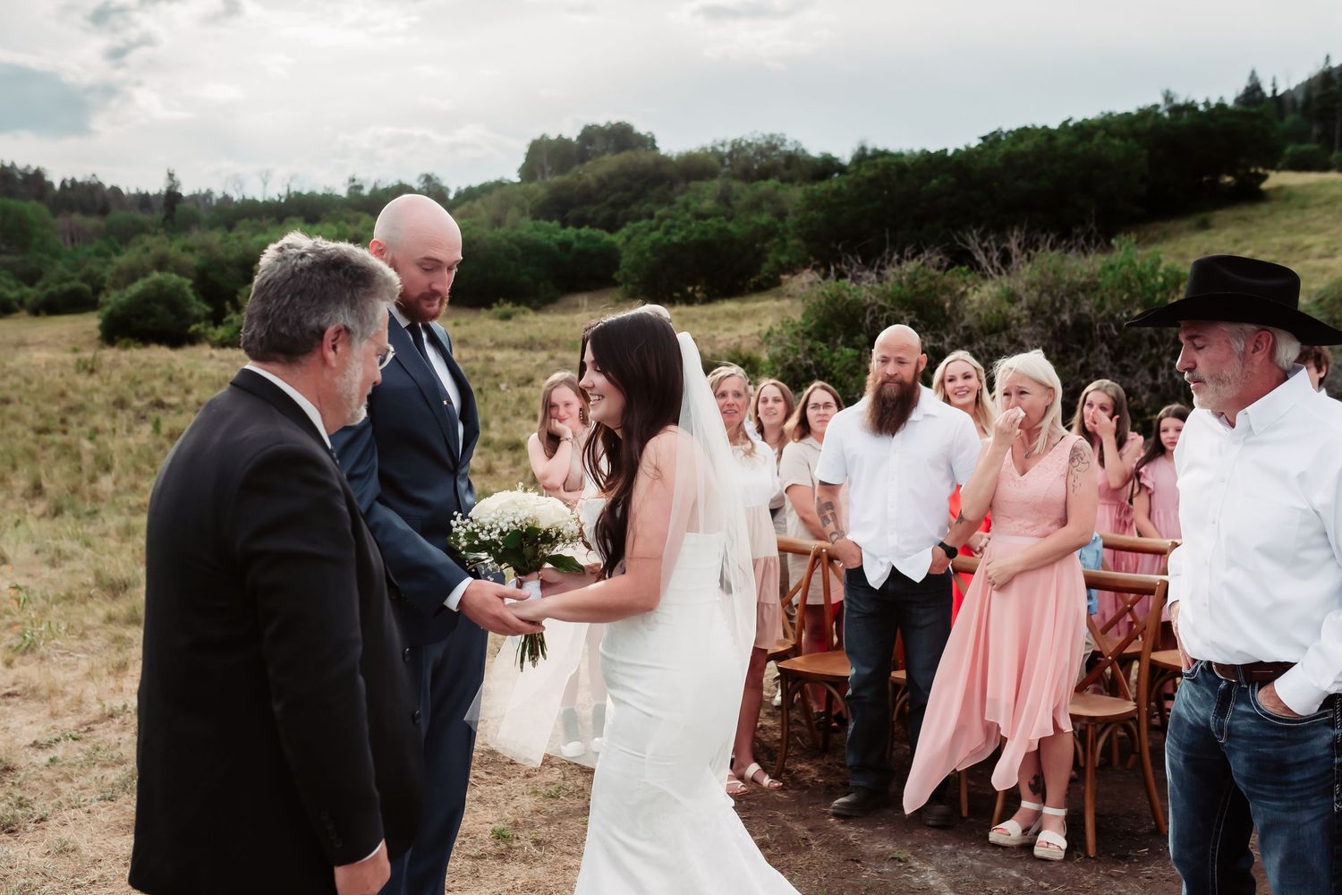 Outdoor wedding ceremony setup with wooden chairs against a mountain backdrop.
