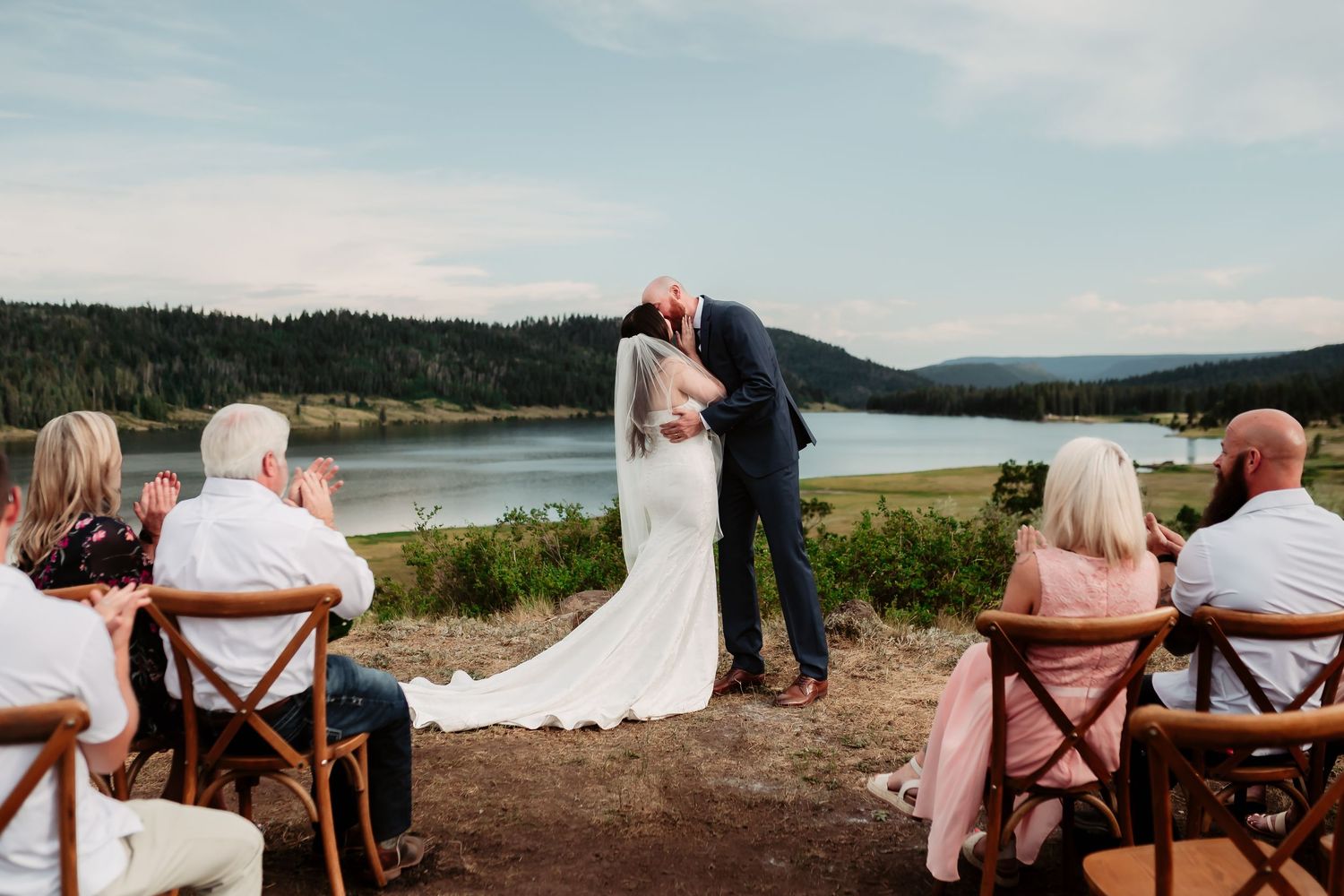 Panoramic view of a mountain wedding ceremony with rustic wooden chairs and natural scenery.