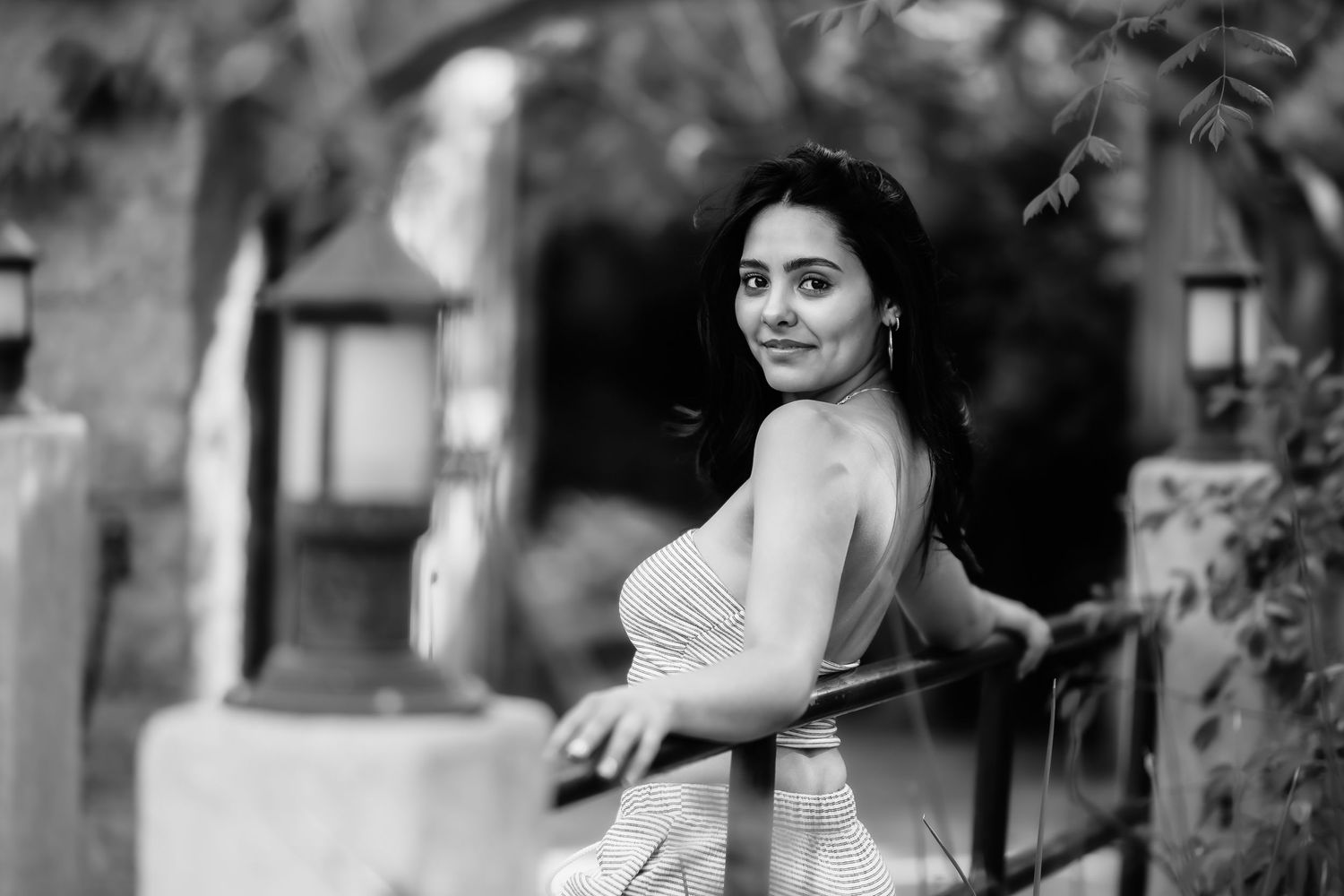Black and white portrait of a person looking over their shoulder with lanterns in the background.