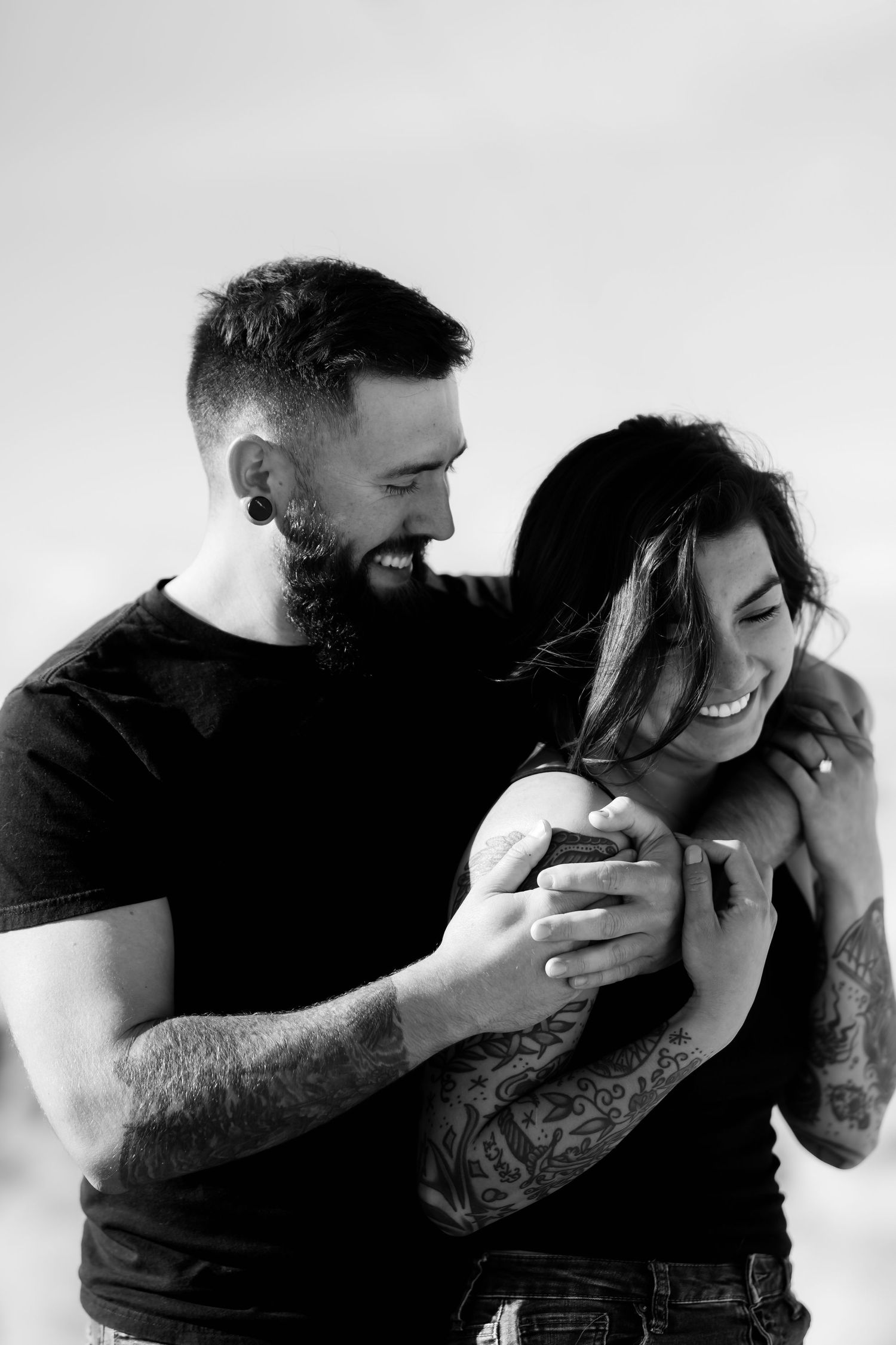A black and white intimate portrait of a couple sharing a joyful candid moment together.