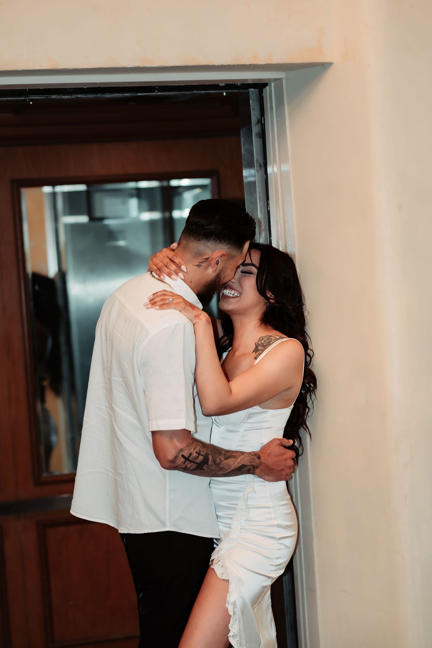 Couple shares tender moment in doorway during wedding photoshoot.