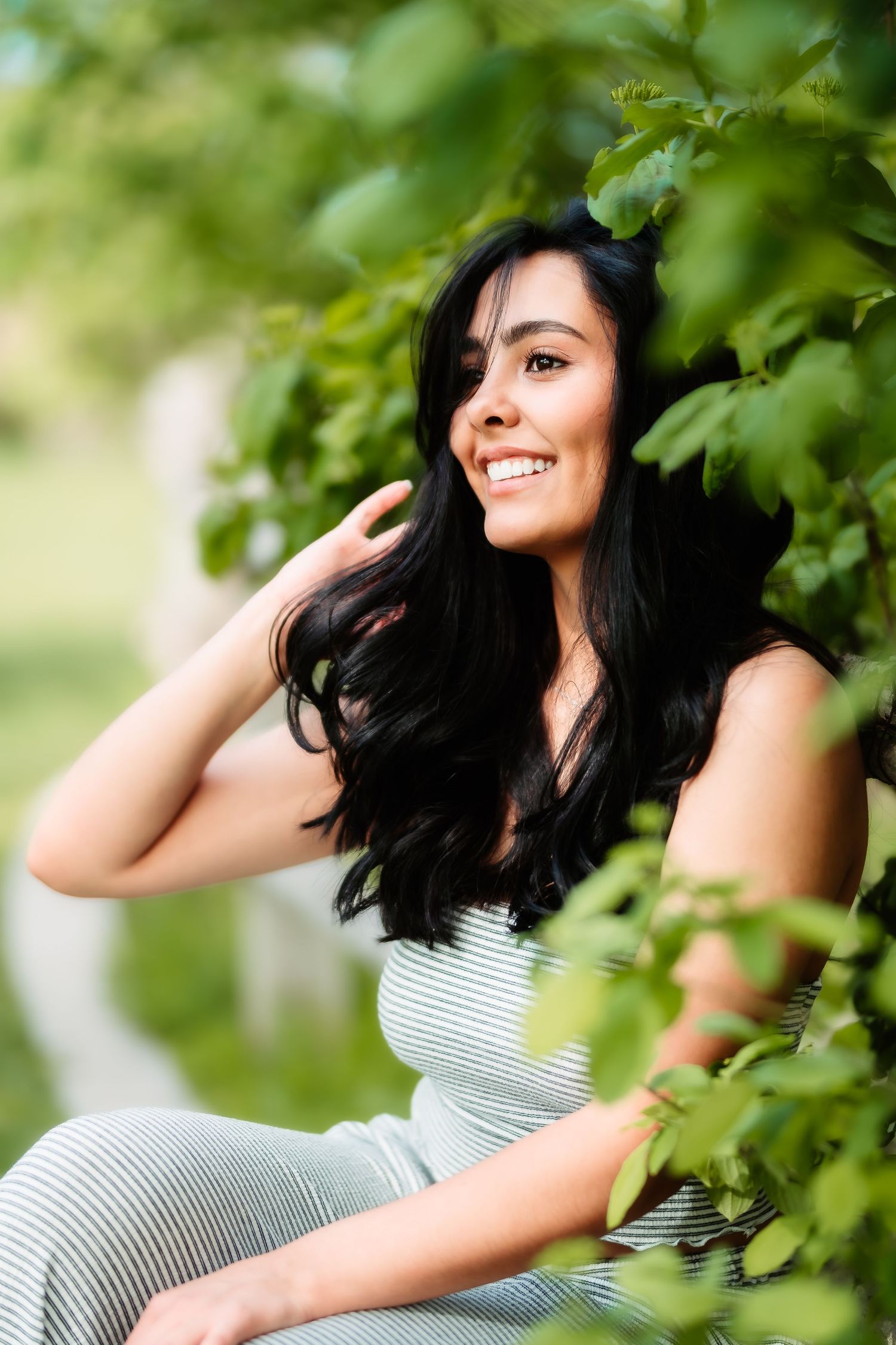 Portrait against green foliage wearing a striped summer outfit.
