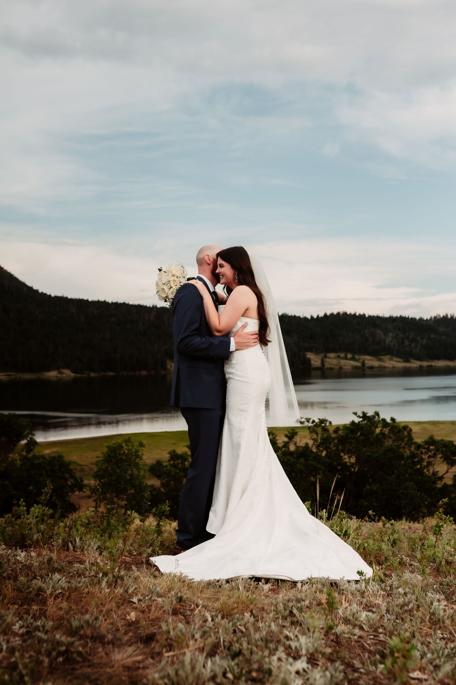 A romantic wedding portrait with a stunning lake and mountain landscape in the background.