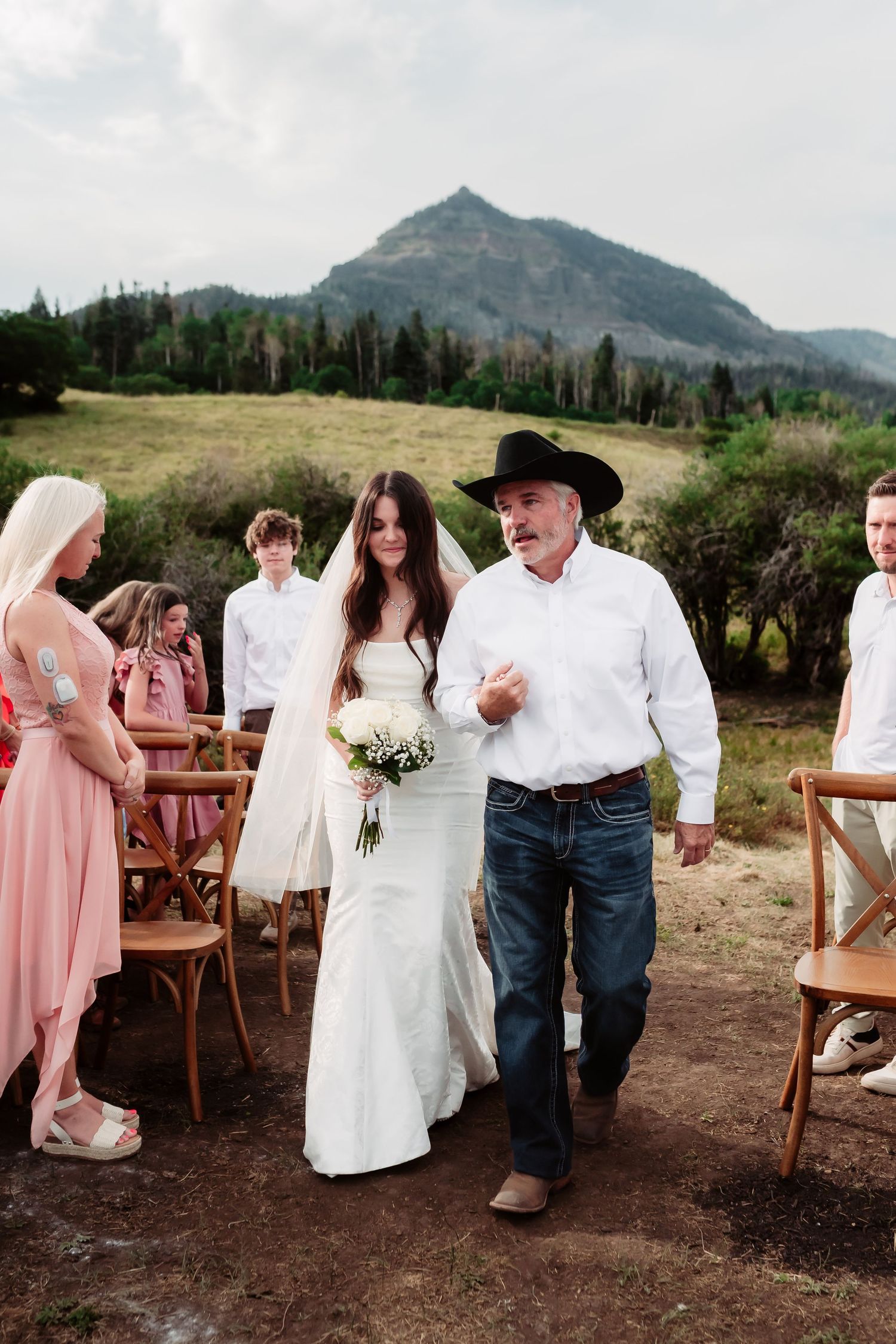 A rustic mountain wedding ceremony with wooden chairs and stunning peak views.