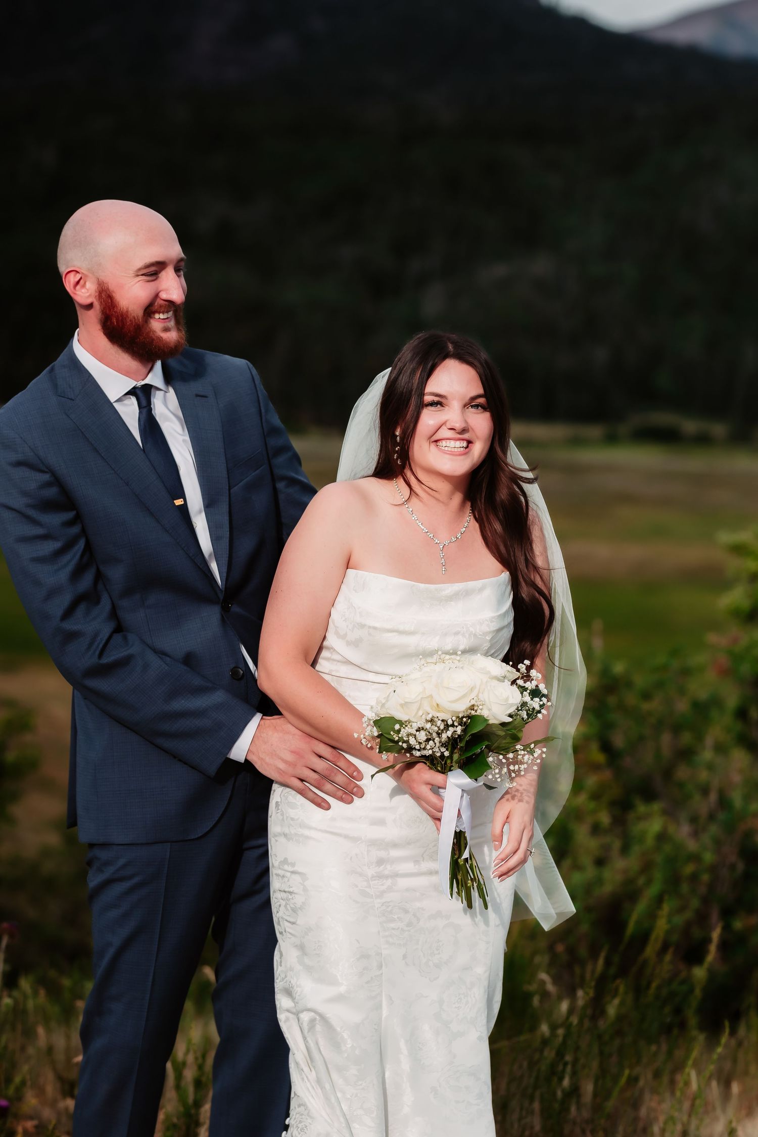 A couple shares an intimate moment during their wedding photoshoot in a mountain setting.