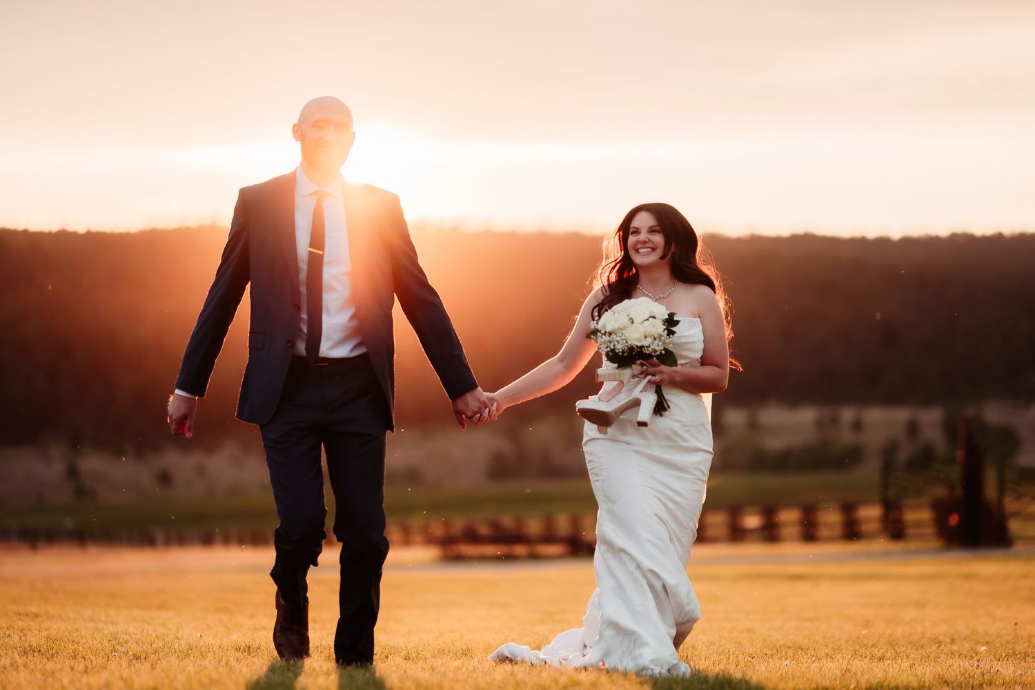 A romantic sunset wedding photoshoot in a golden field with dramatic lighting.