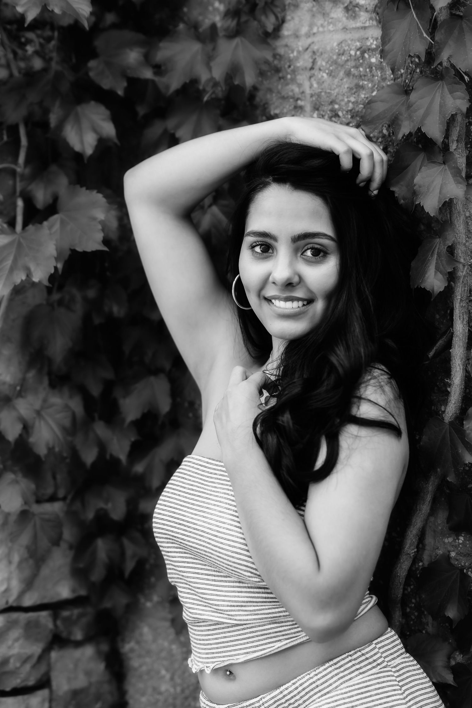 Dramatic black and white portrait against textured ivy-covered wall background.