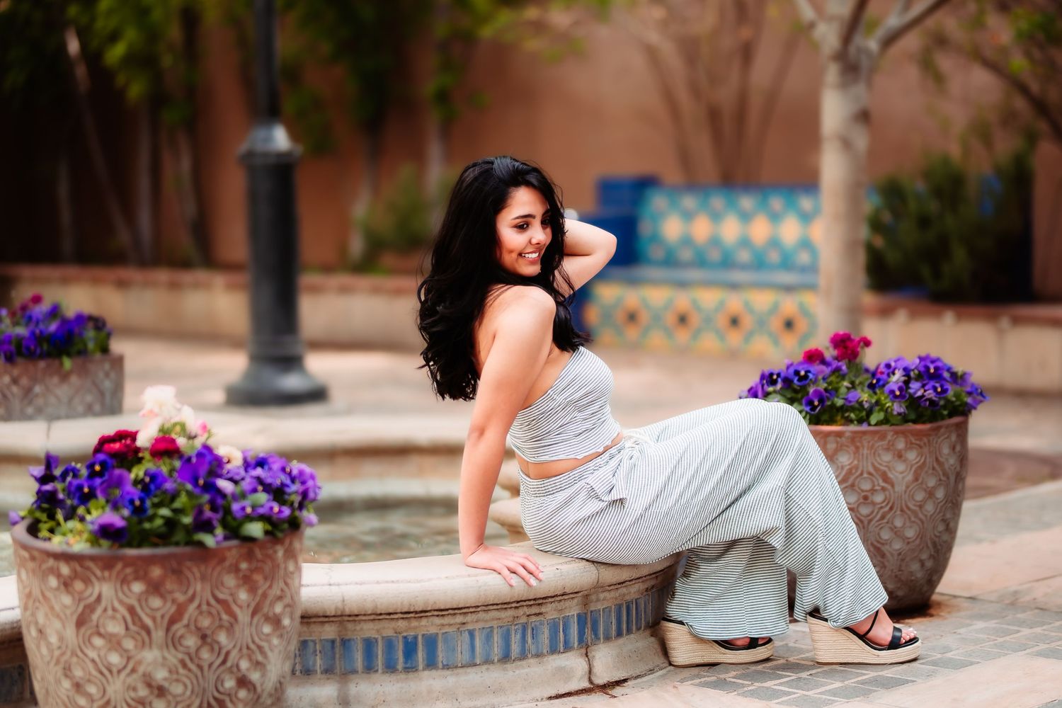 A casual outdoor portrait near decorative flower pots and tiled walls.