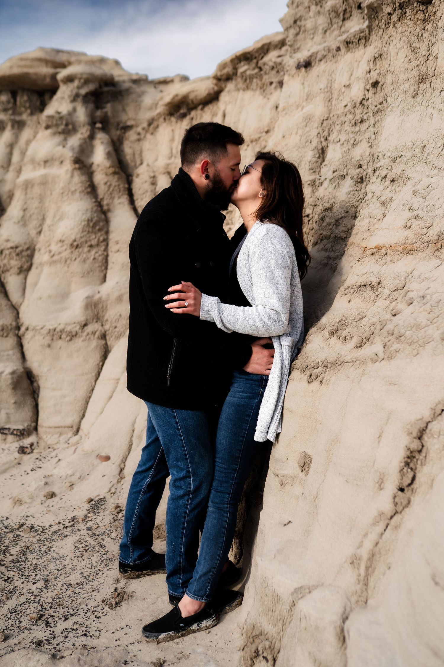 Couple sharing an intimate moment against textured rock formations in a desert landscape.