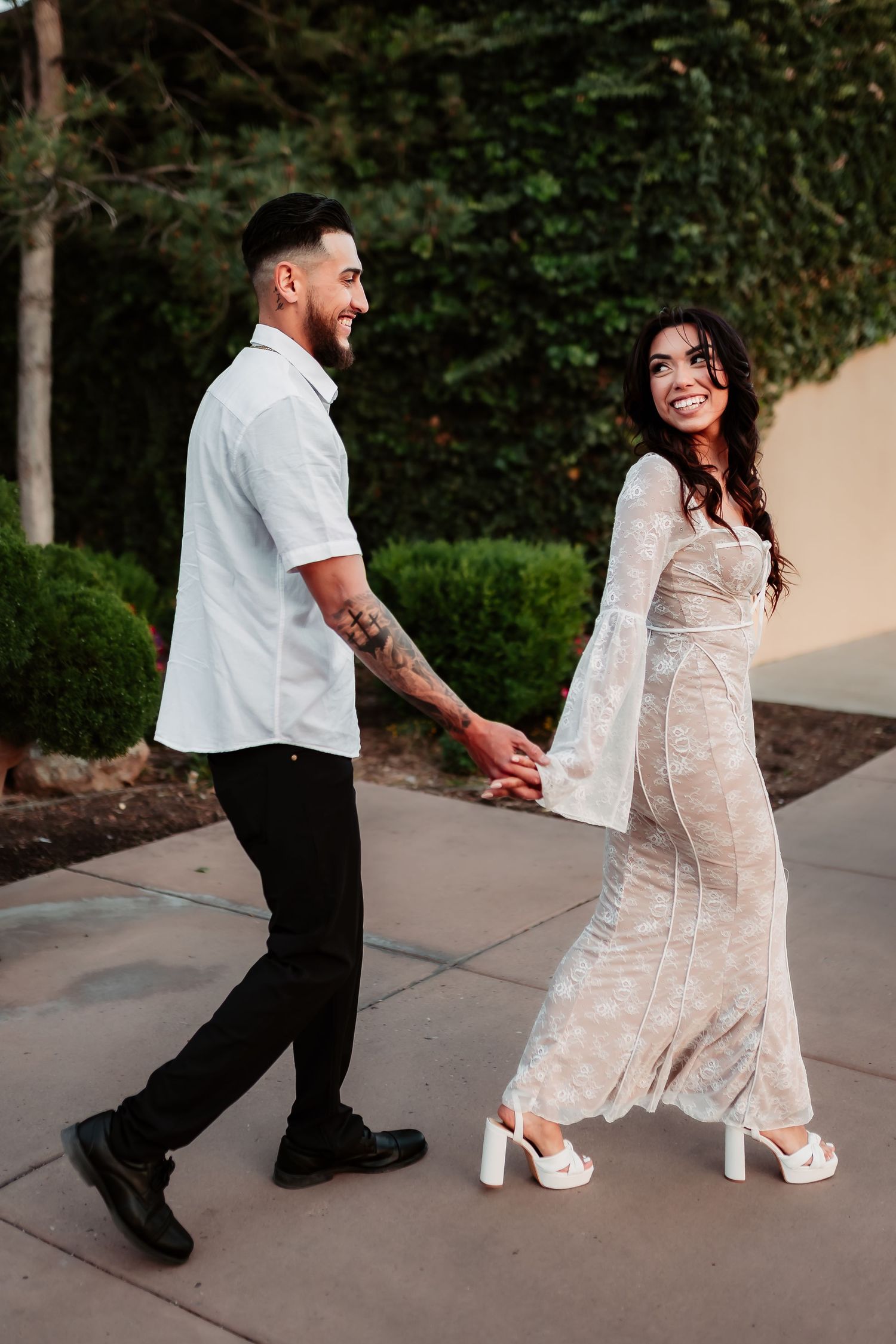 A couple walking together outdoors in coordinated white outfits.