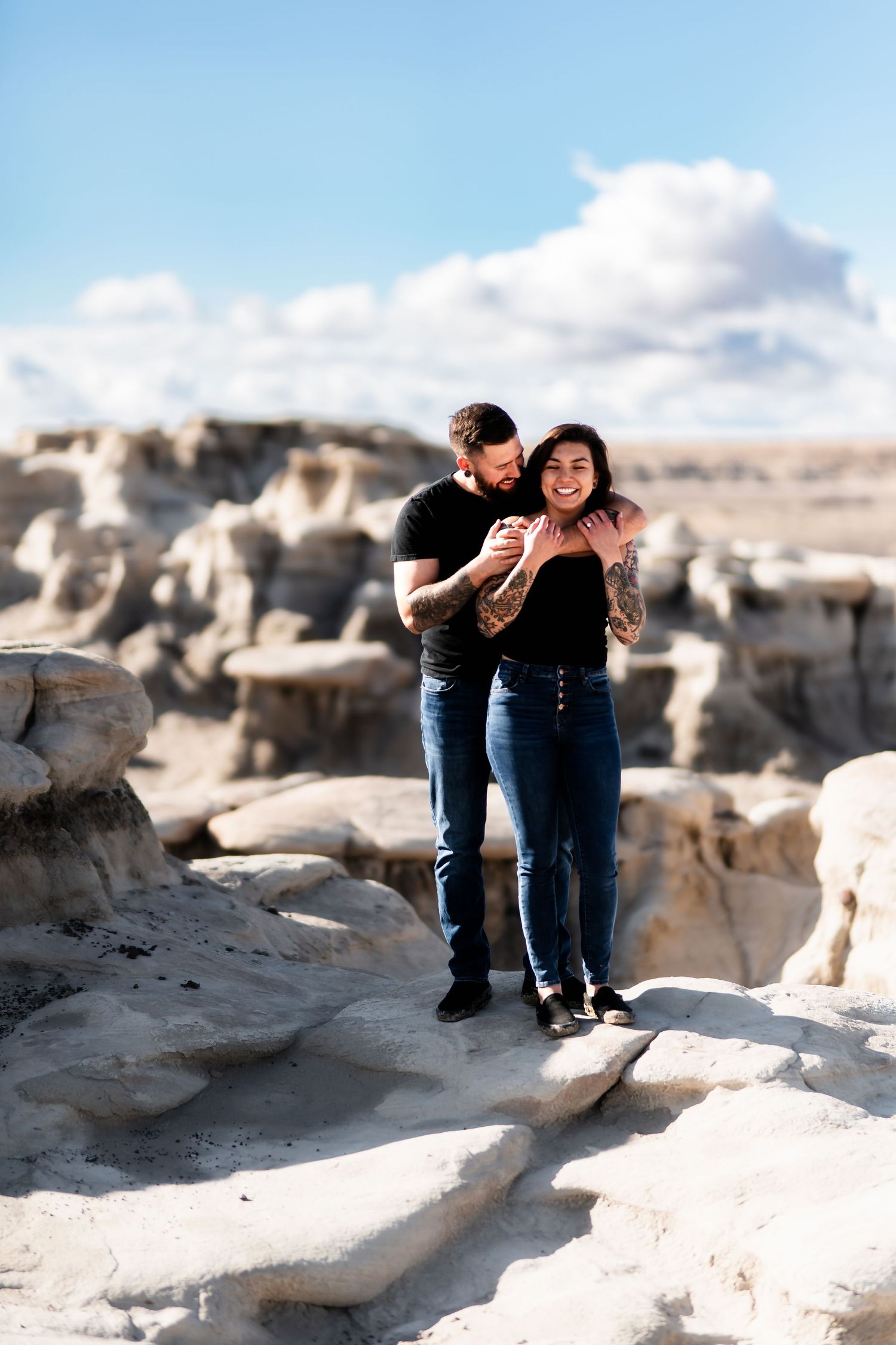 A couple shares a lighthearted moment while exploring rocky desert terrain.