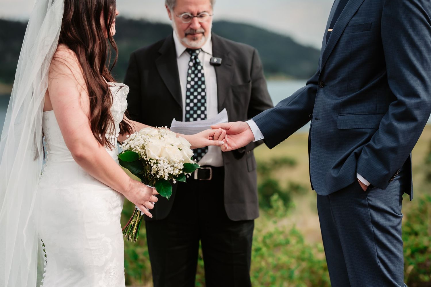 Wedding ceremony participants stand together against a mountainous backdrop during an outdoor ceremony.