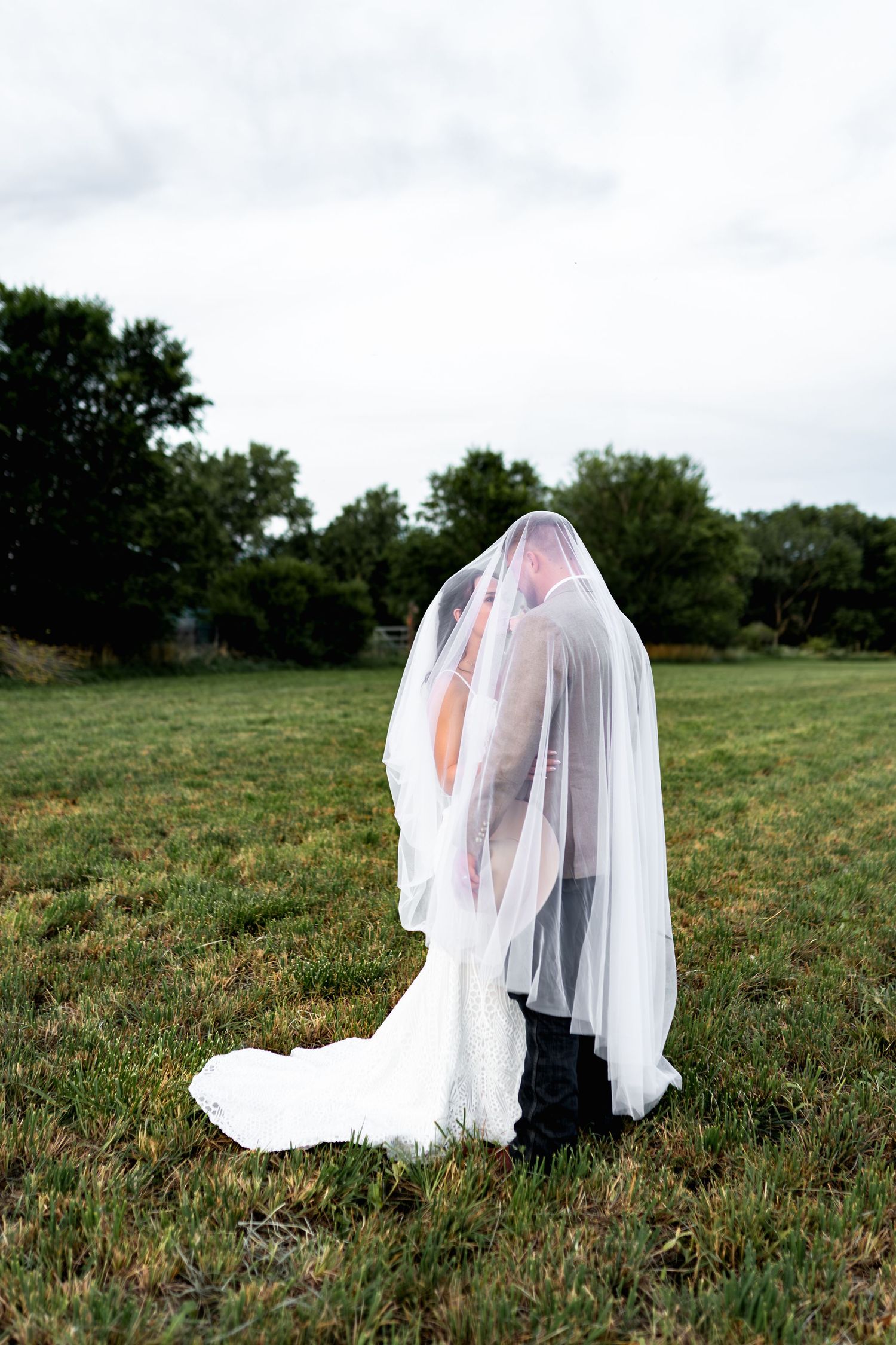 Romantic wedding portrait of couple sharing an intimate moment under a flowing white veil.