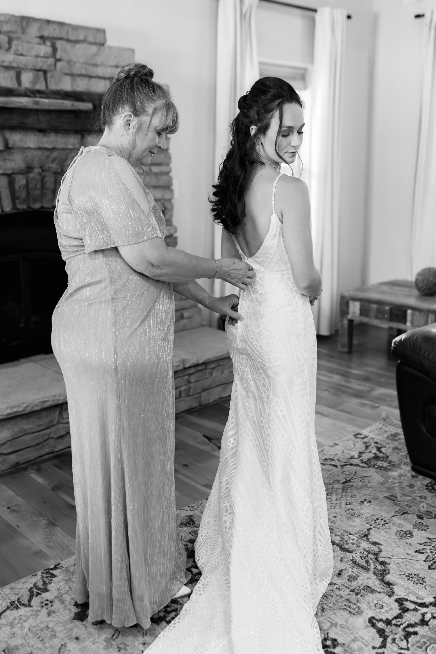 A bride gets help with her fitted lace wedding dress before the ceremony.