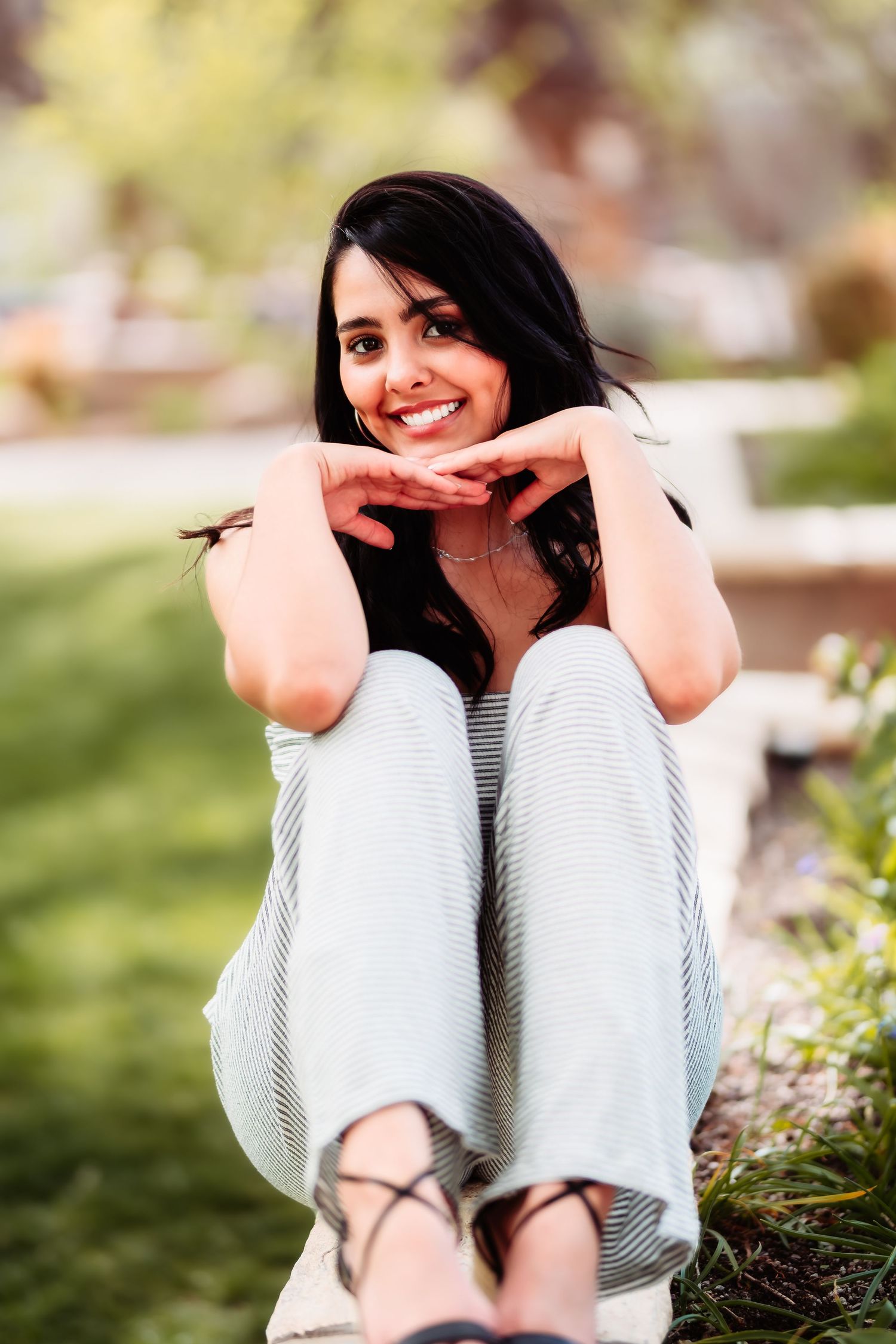 Casual portrait of someone in striped clothing resting chin on hands with a warm expression.