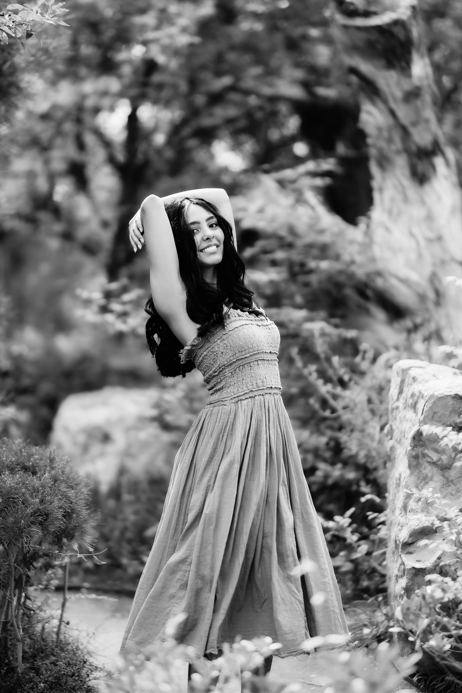 Dramatic black and white pose against stone walls and garden elements.