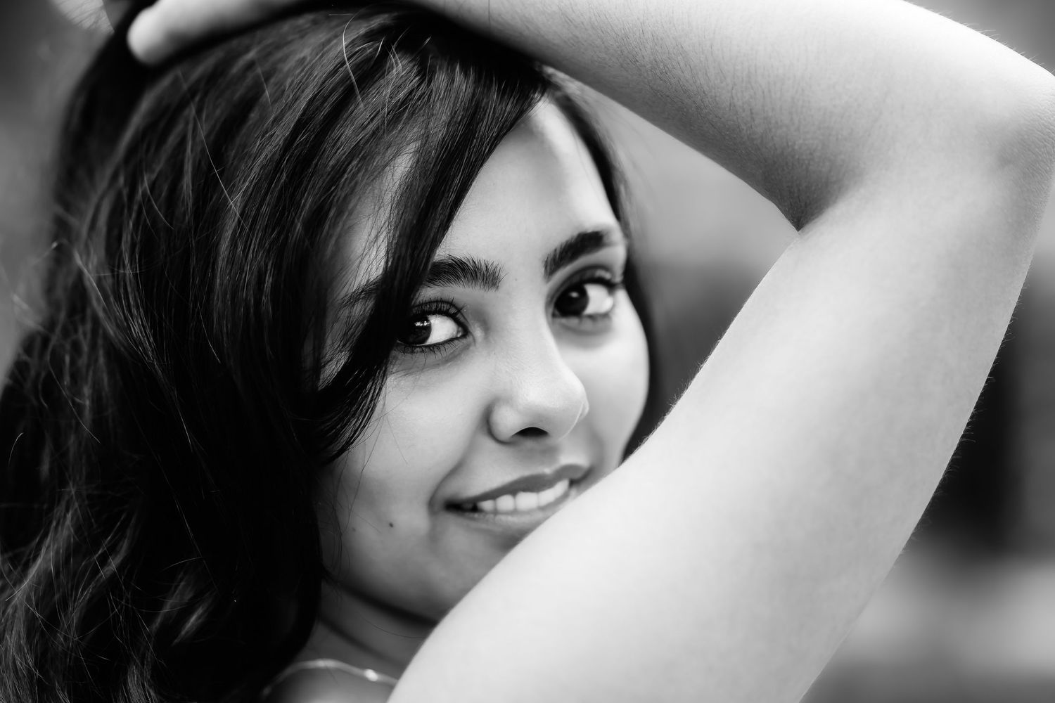 Black and white portrait with natural lighting and soft smile.