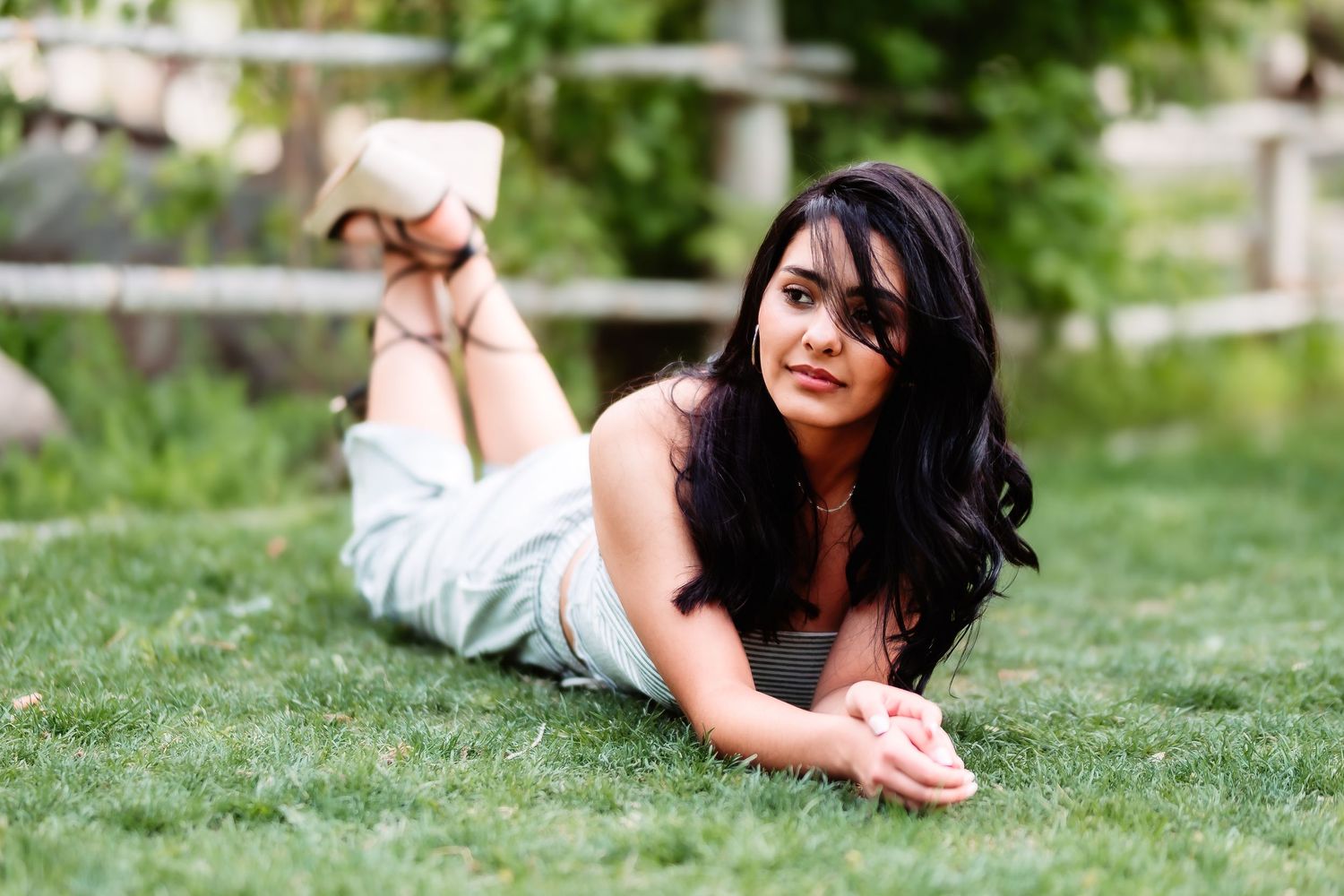 A relaxed pose on green grass wearing white clothing during an outdoor photo session.