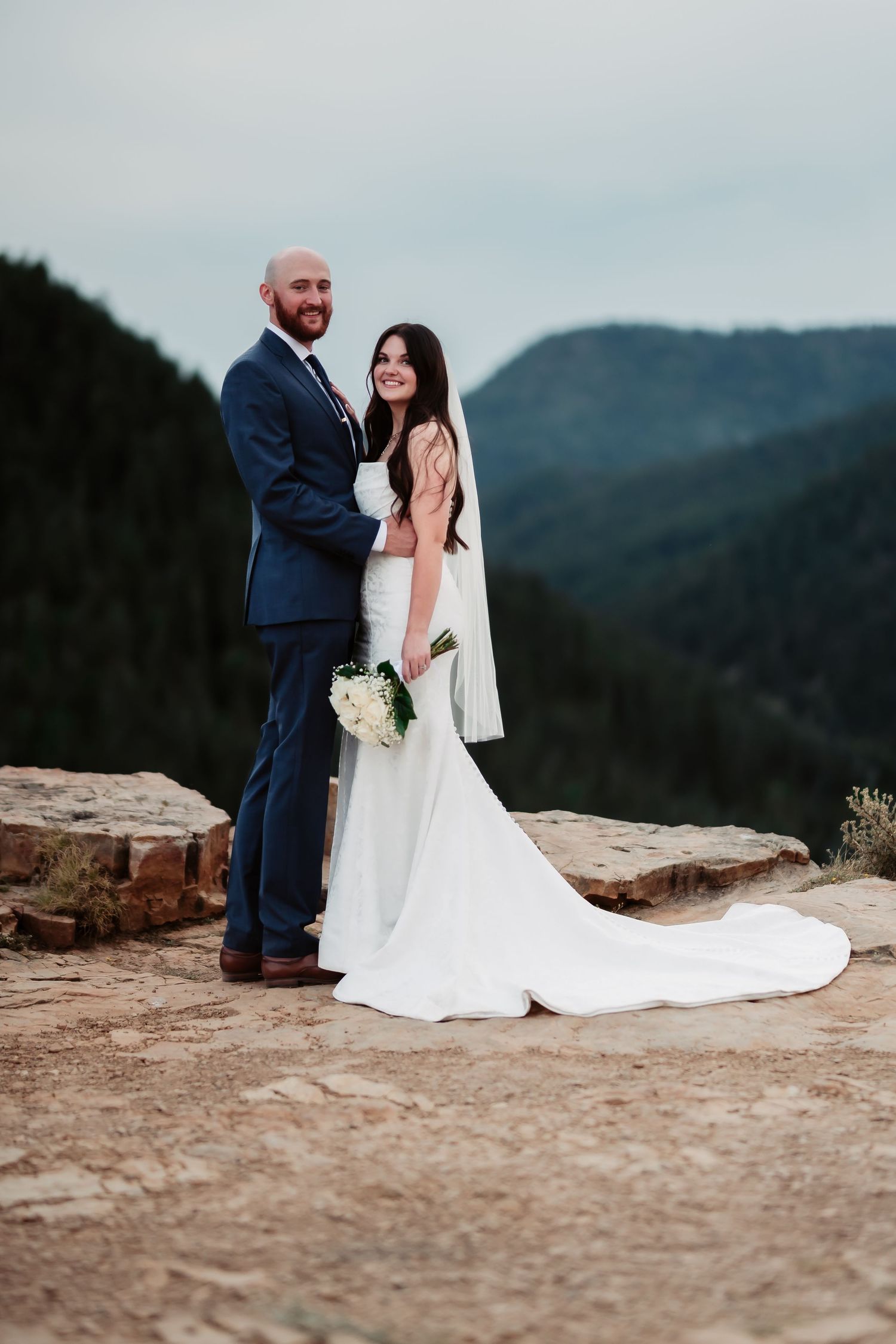 Wedding couple shares tender moments on a scenic mountain overlook during sunset.