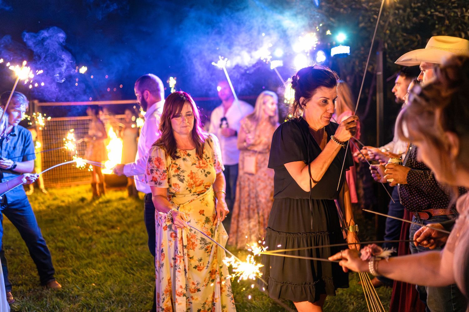 Wedding celebration at night with guests holding sparklers creating a magical outdoor atmosphere.
