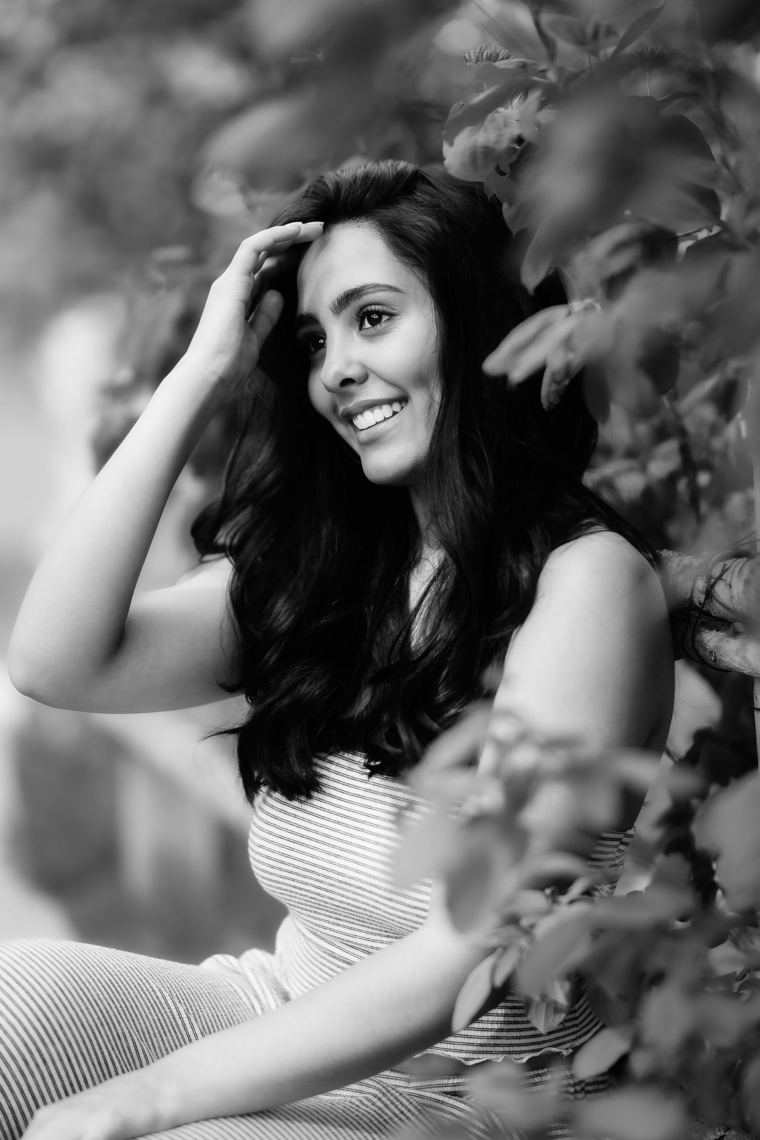 Candid black and white portrait with natural lighting showing genuine joy among leaves.