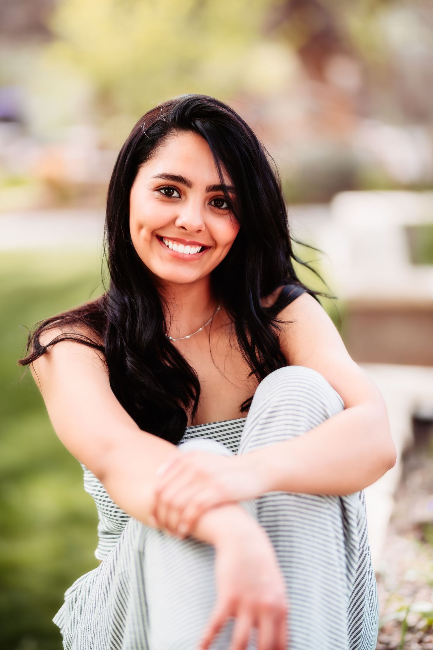 A casual outdoor portrait features a striped top and relaxed pose in a garden setting.