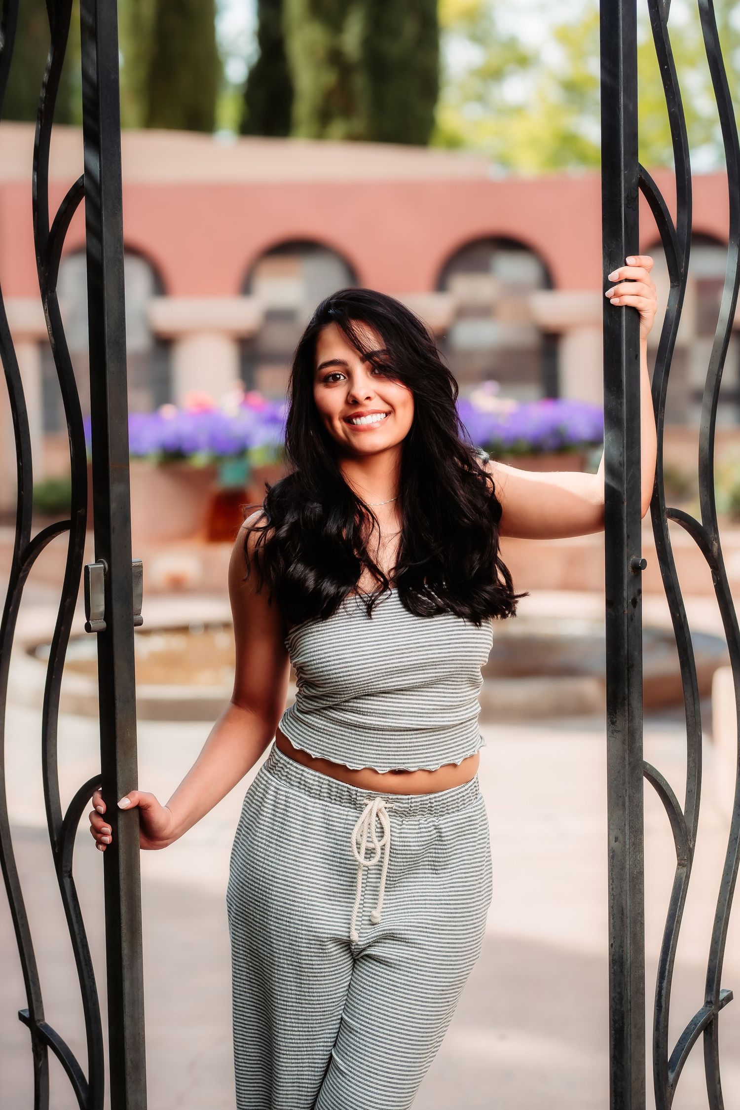 Person in matching gray loungewear poses playfully between decorative iron gates.