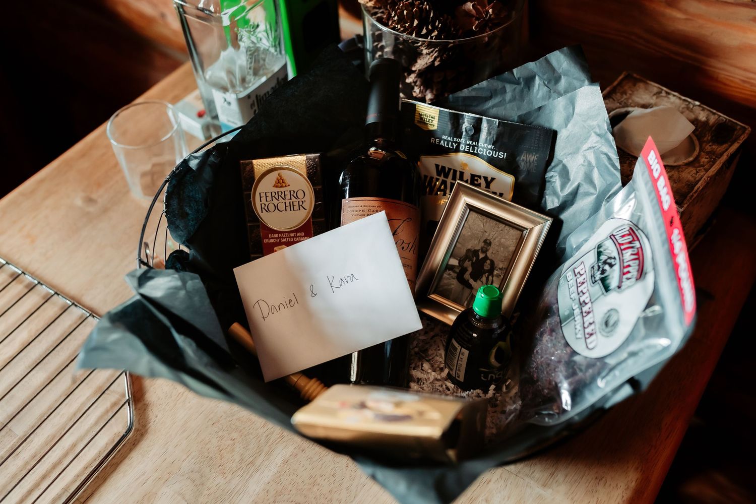 Gift basket filled with various wrapped items and packages on wooden surface.