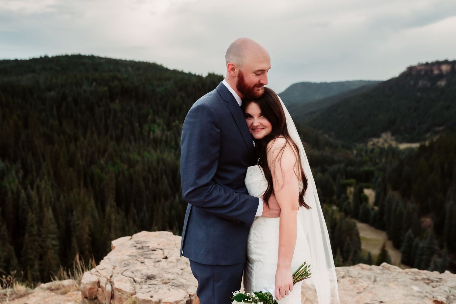 A tender wedding moment shared between a couple on a mountain overlook.