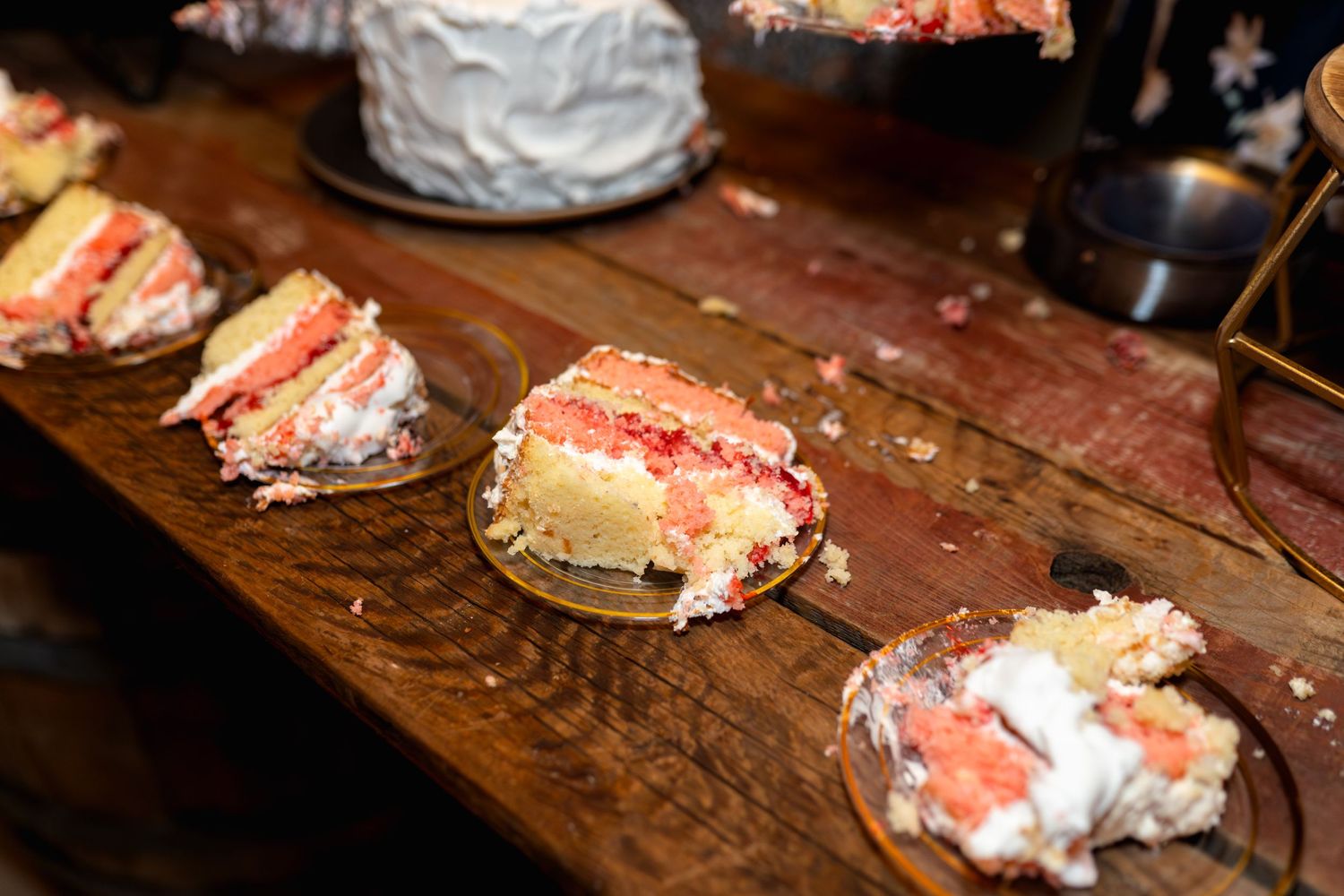 Slices of pink wedding cake displayed on wooden serving board.