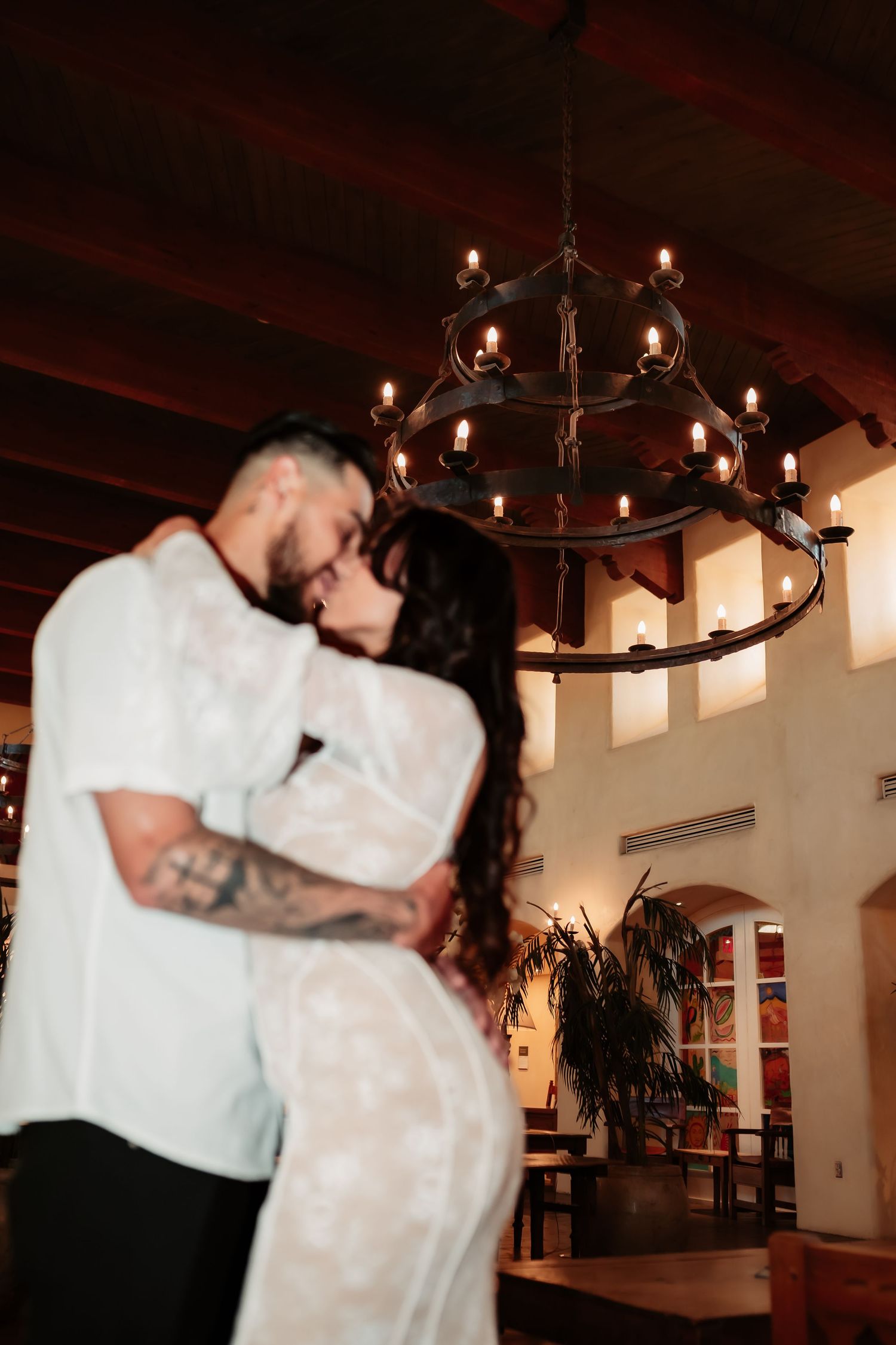 Intimate dance moment under a rustic chandelier in a warmly lit room.