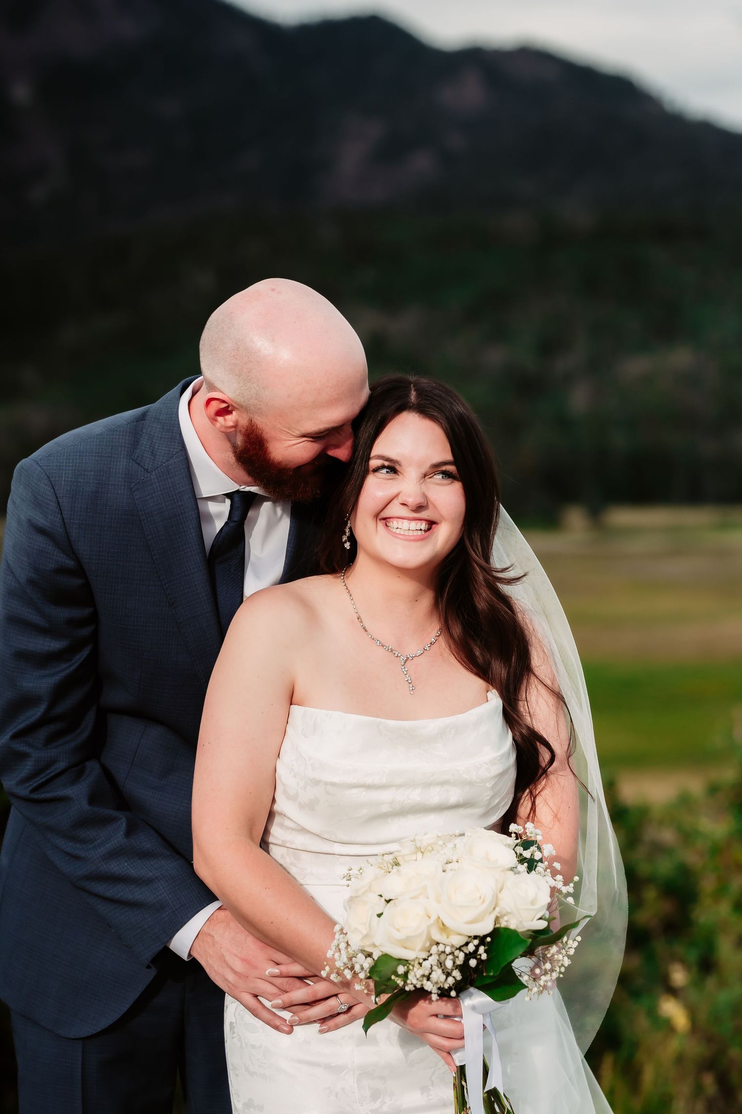 A joyful wedding couple shares intimate moments during their mountain ceremony photoshoot.