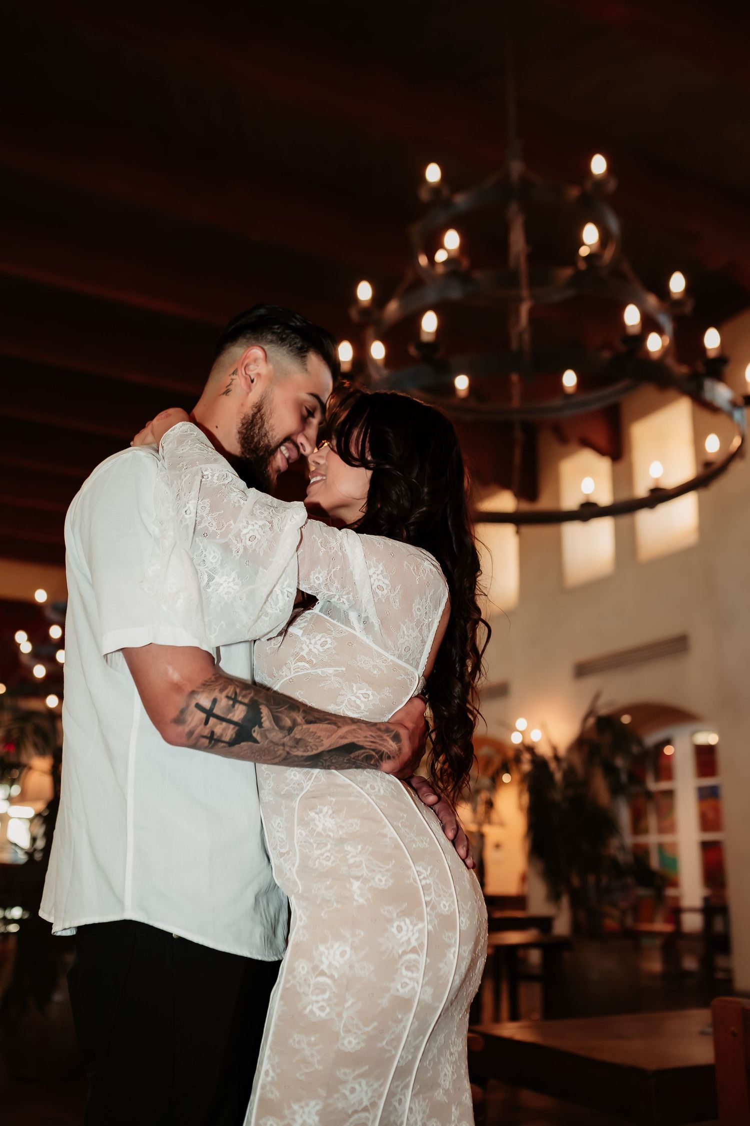 A romantic embrace under a warm chandelier light during a formal celebration.
