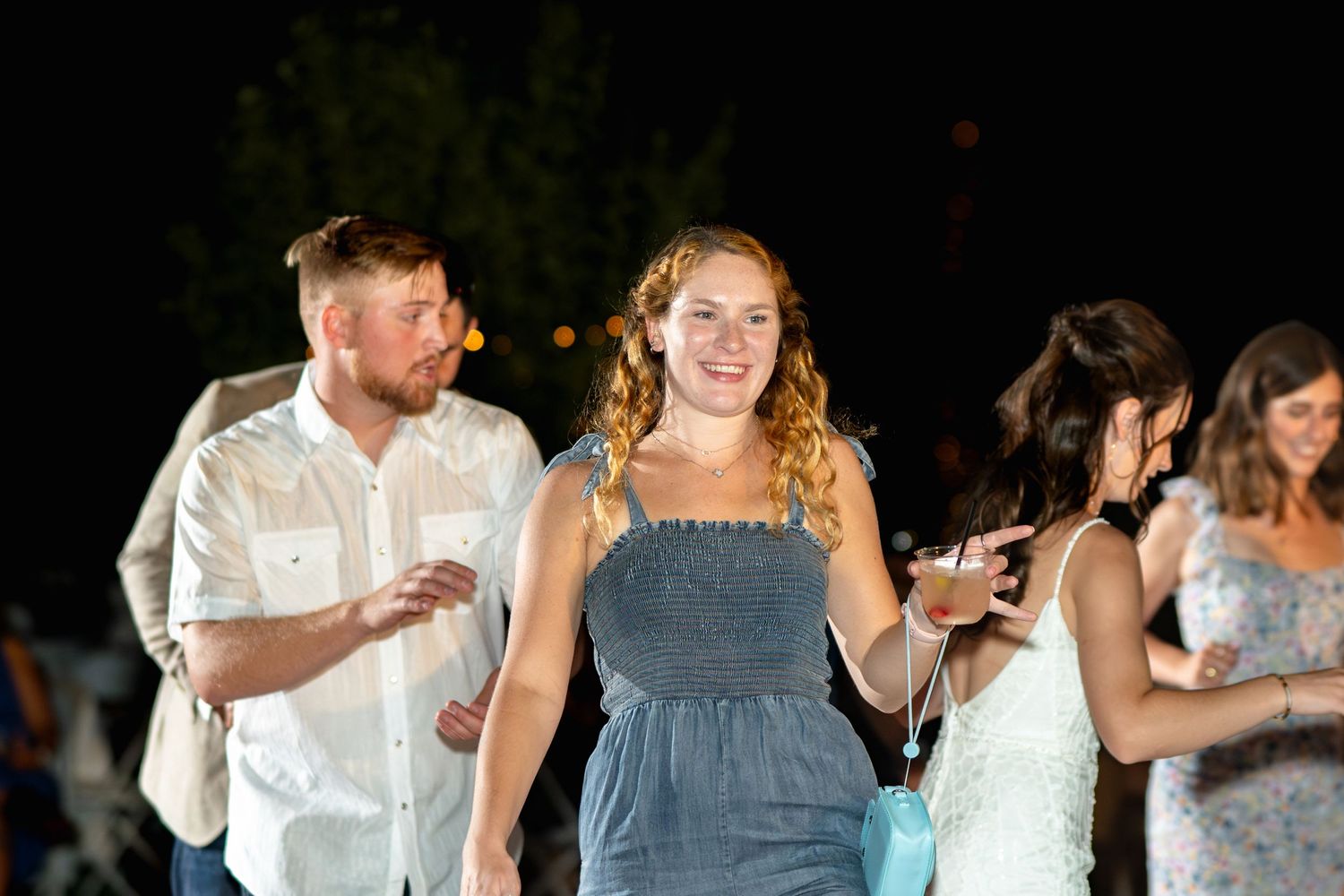 Wedding guests dancing and celebrating at an evening reception.
