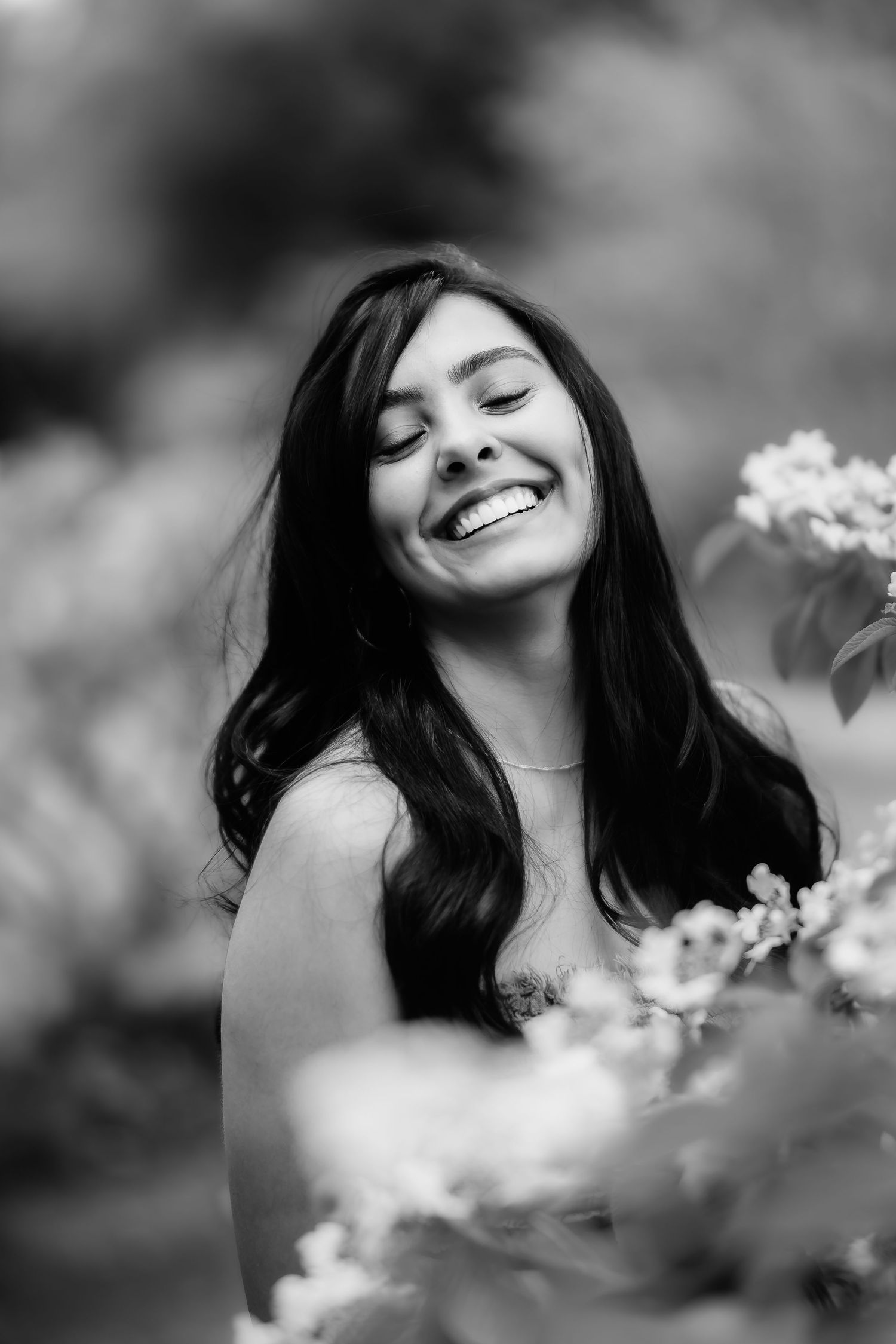 A black and white portrait surrounded by delicate flowers with a joyful expression.