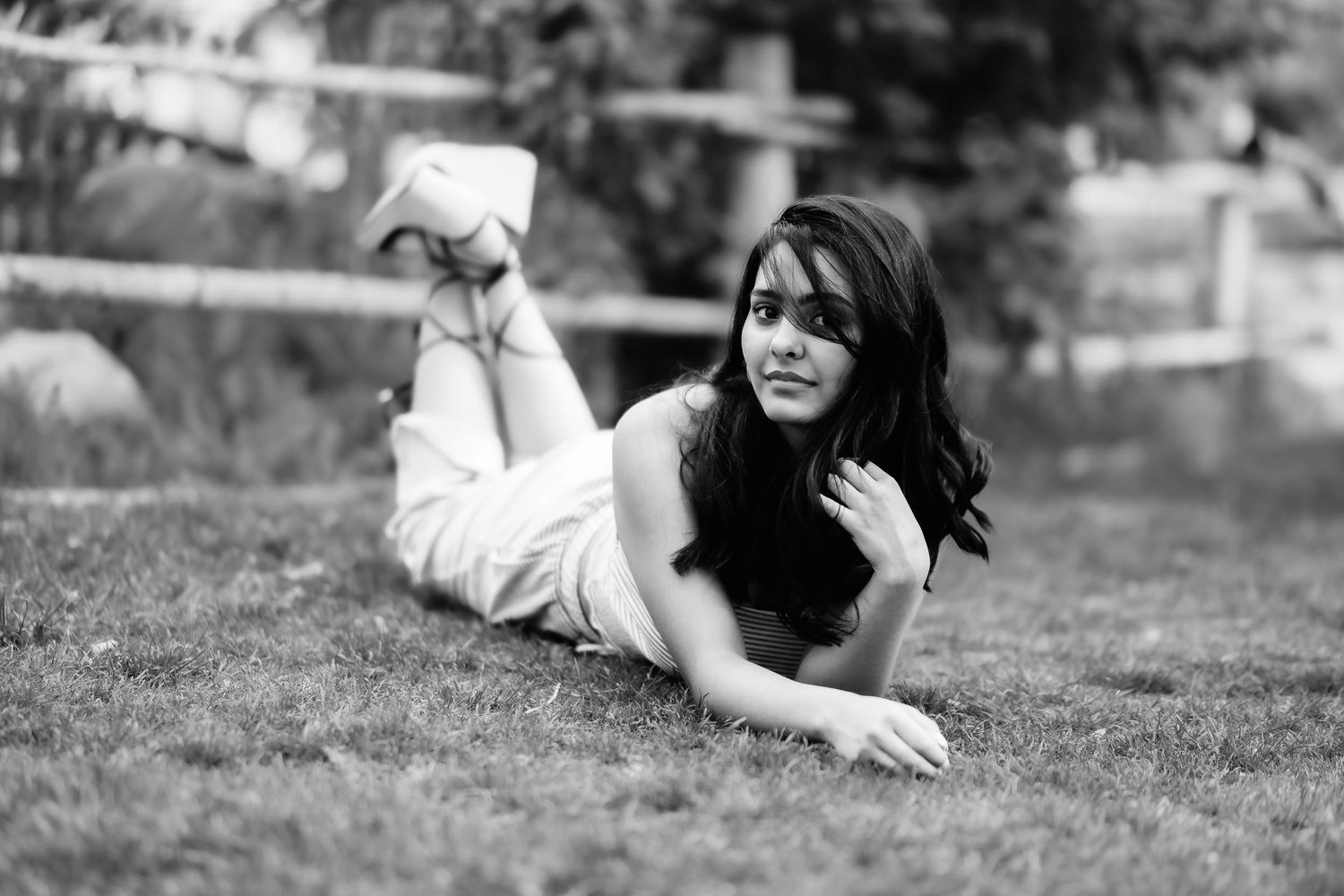 Black and white portrait of woman lying on grass in casual pose.