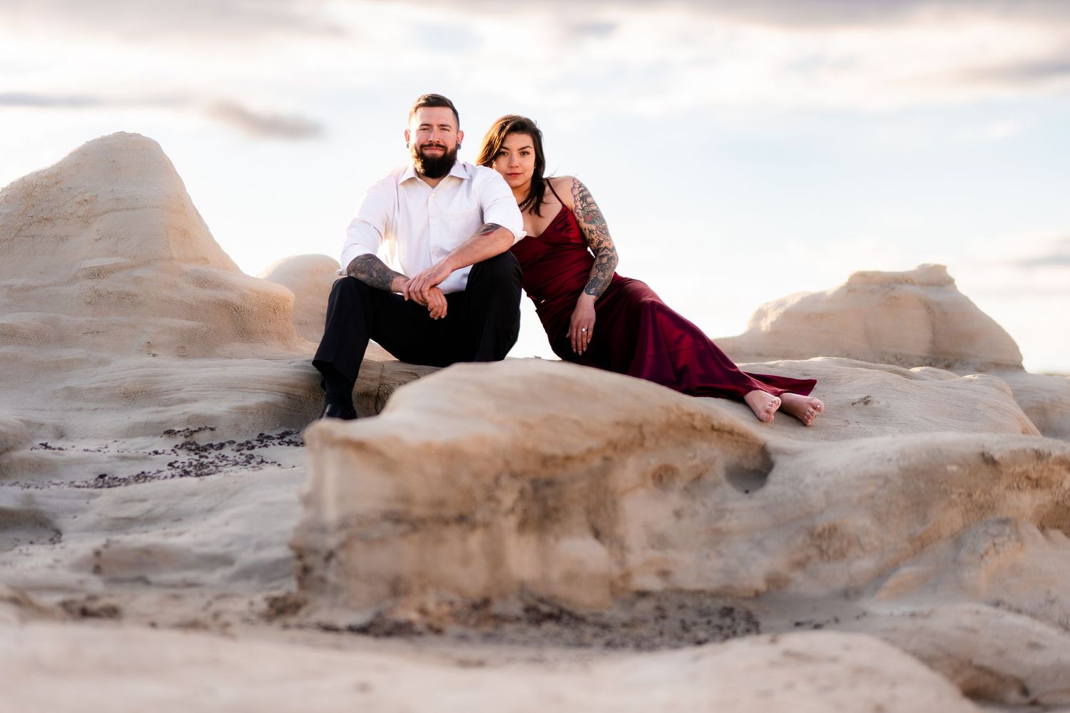 Couple relaxing on smooth desert rock formations during golden hour.