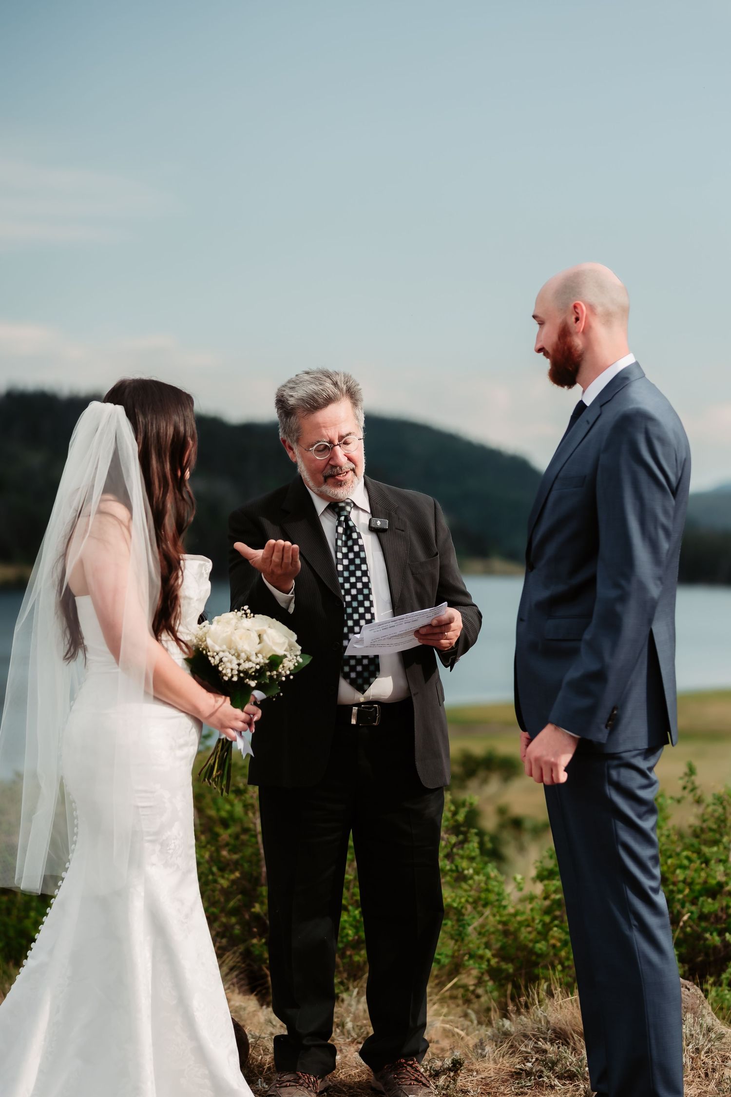 An outdoor wedding ceremony unfolds against a beautiful lakeside backdrop.