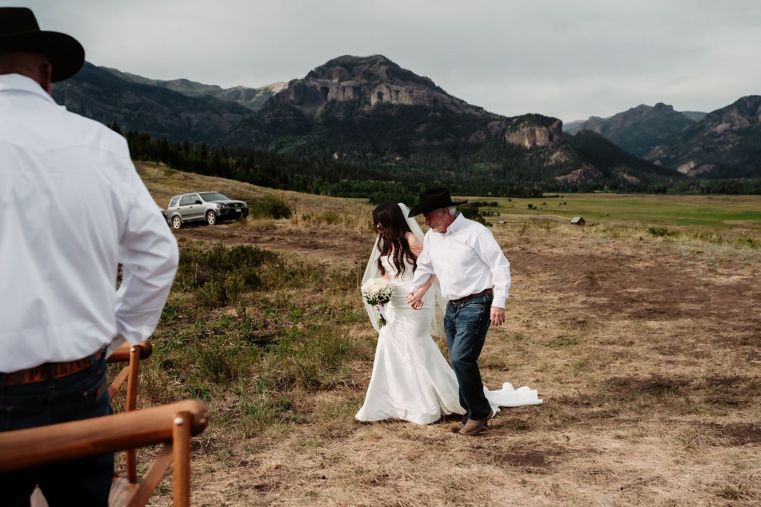 A wedding ceremony unfolds against a dramatic mountain landscape backdrop.