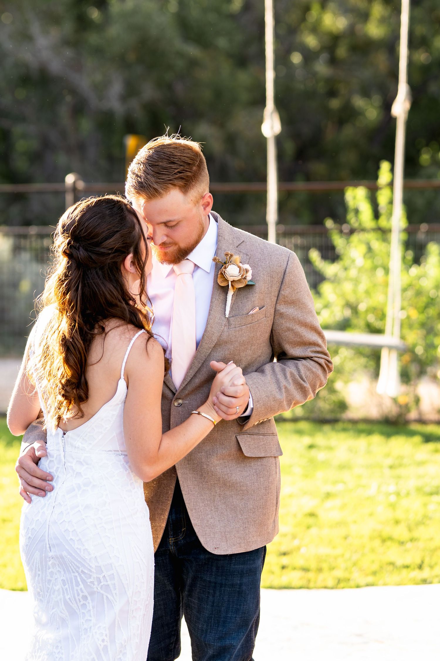 A romantic dance between newlyweds in formal attire during golden hour.