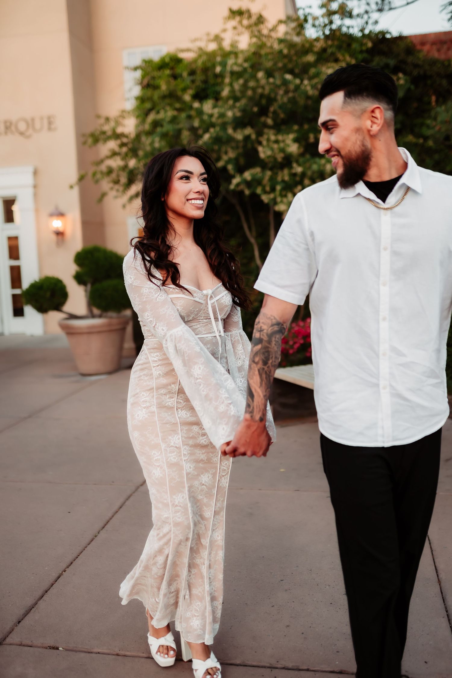 Couple walks together outside venue wearing coordinated white and black outfits.