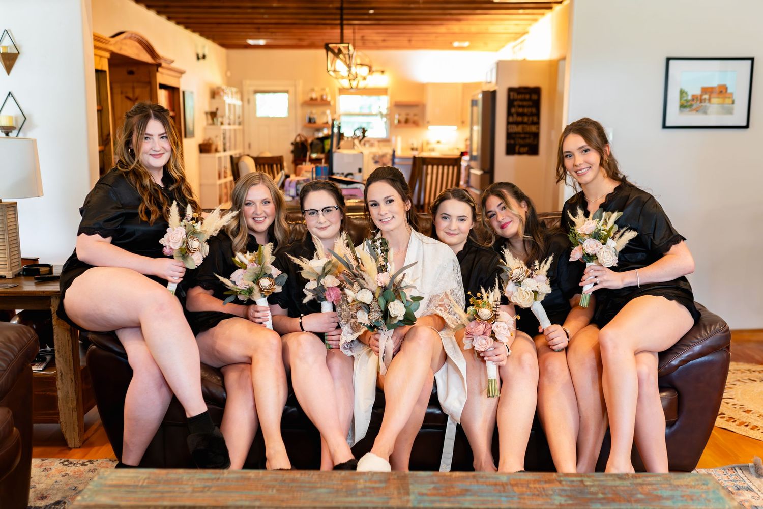 A group gathers on a couch together wearing matching black robes holding small puppies.