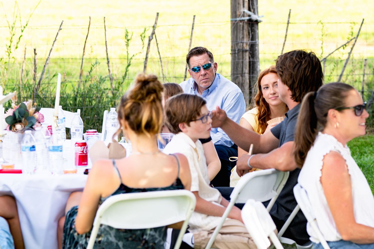 Guests enjoying an outdoor celebration at decorated tables with white linens.