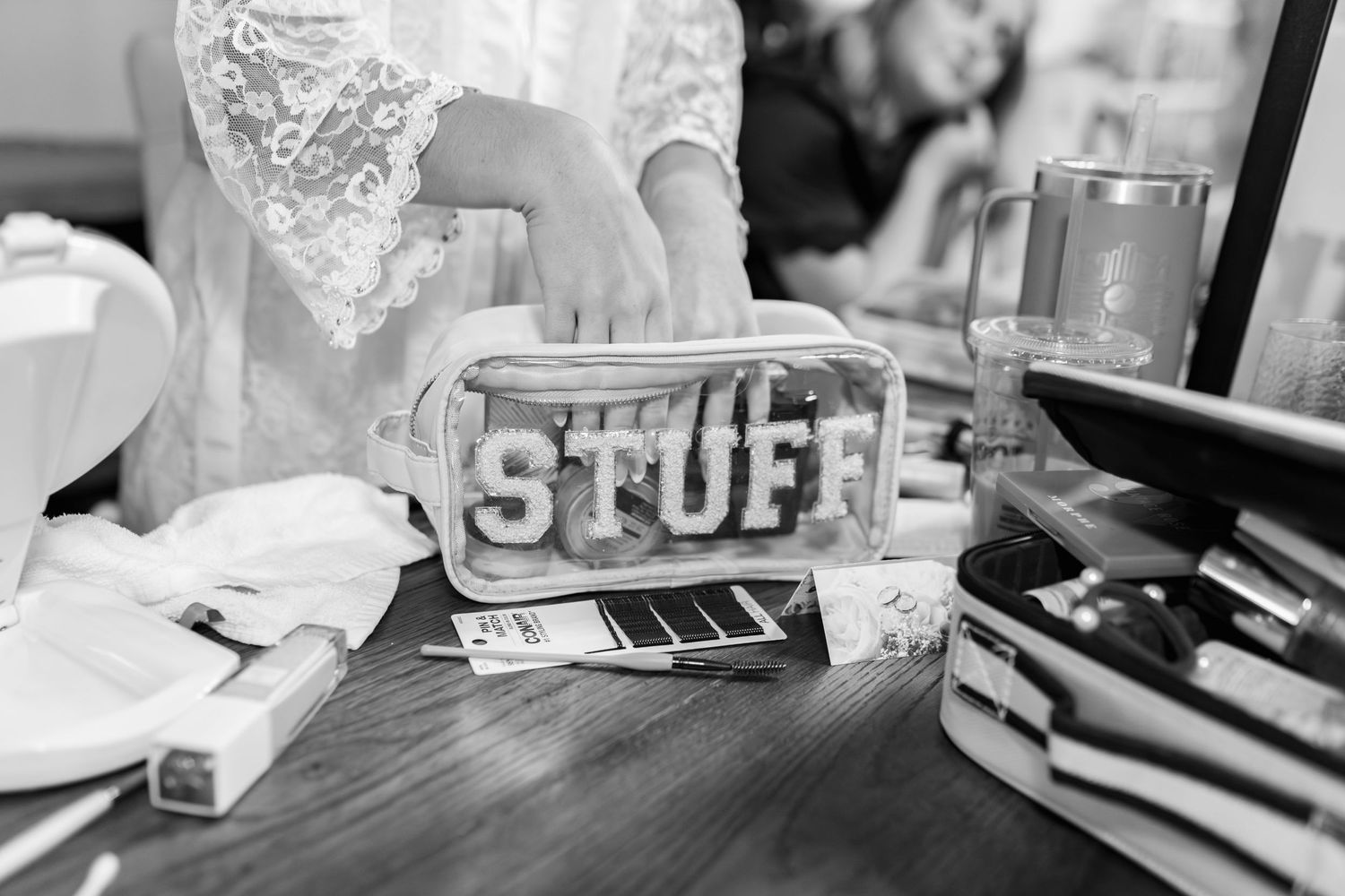 Black and white detail shot of wedding decor and personal items on a table.