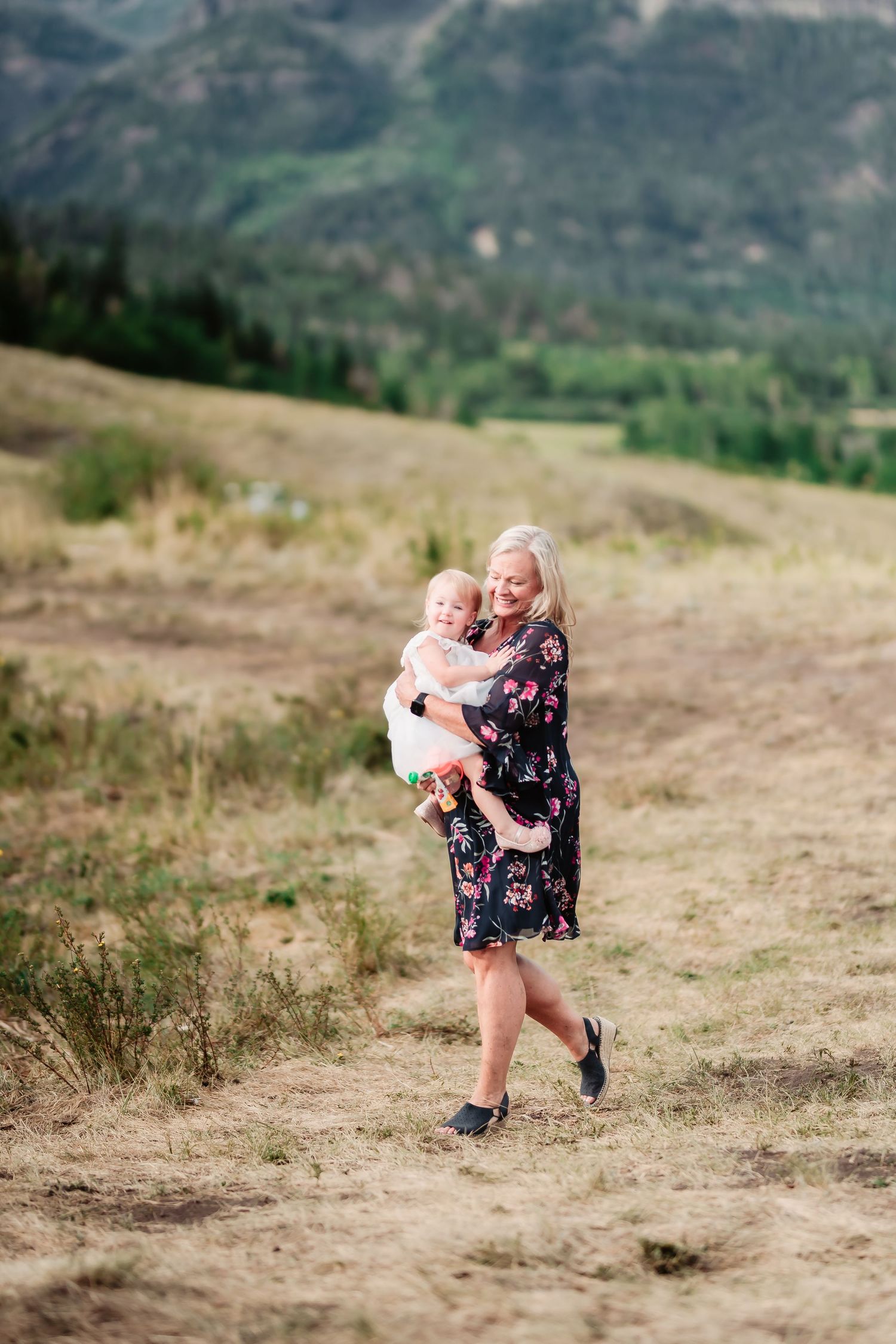 A joyful moment captured on a hillside with mountains in the background.