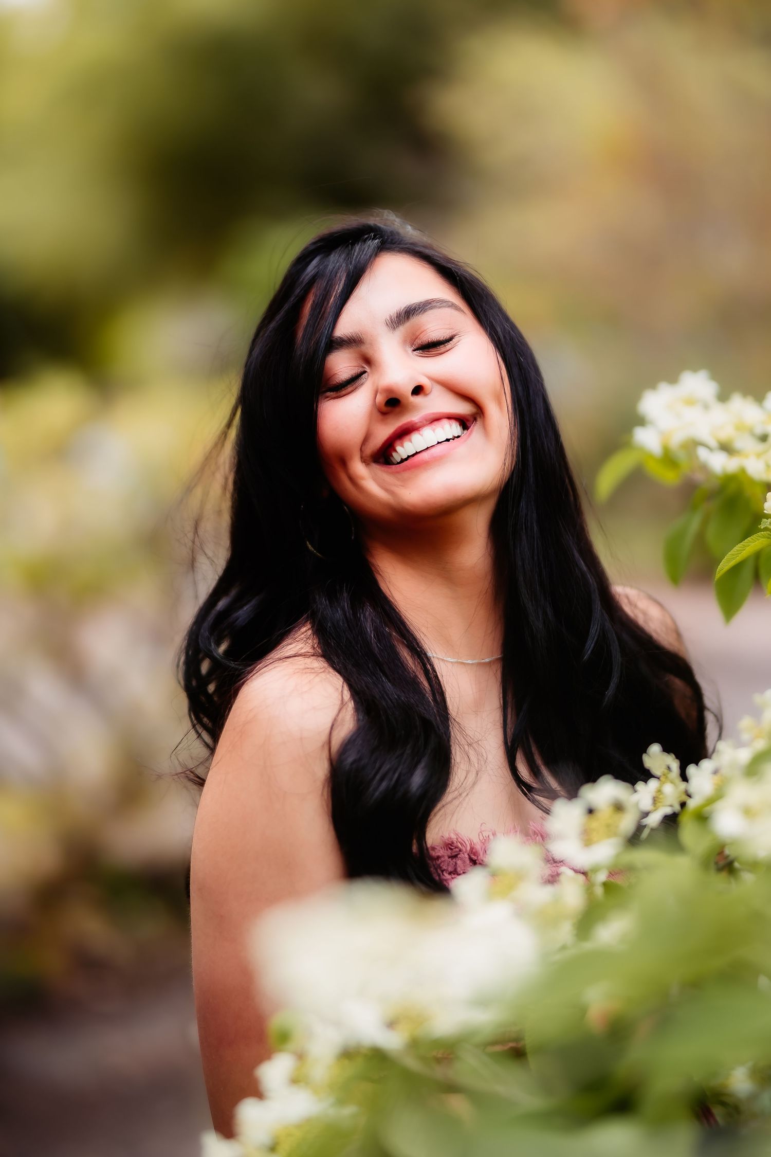 Joyful portrait through blooming white flowers in a natural outdoor setting.